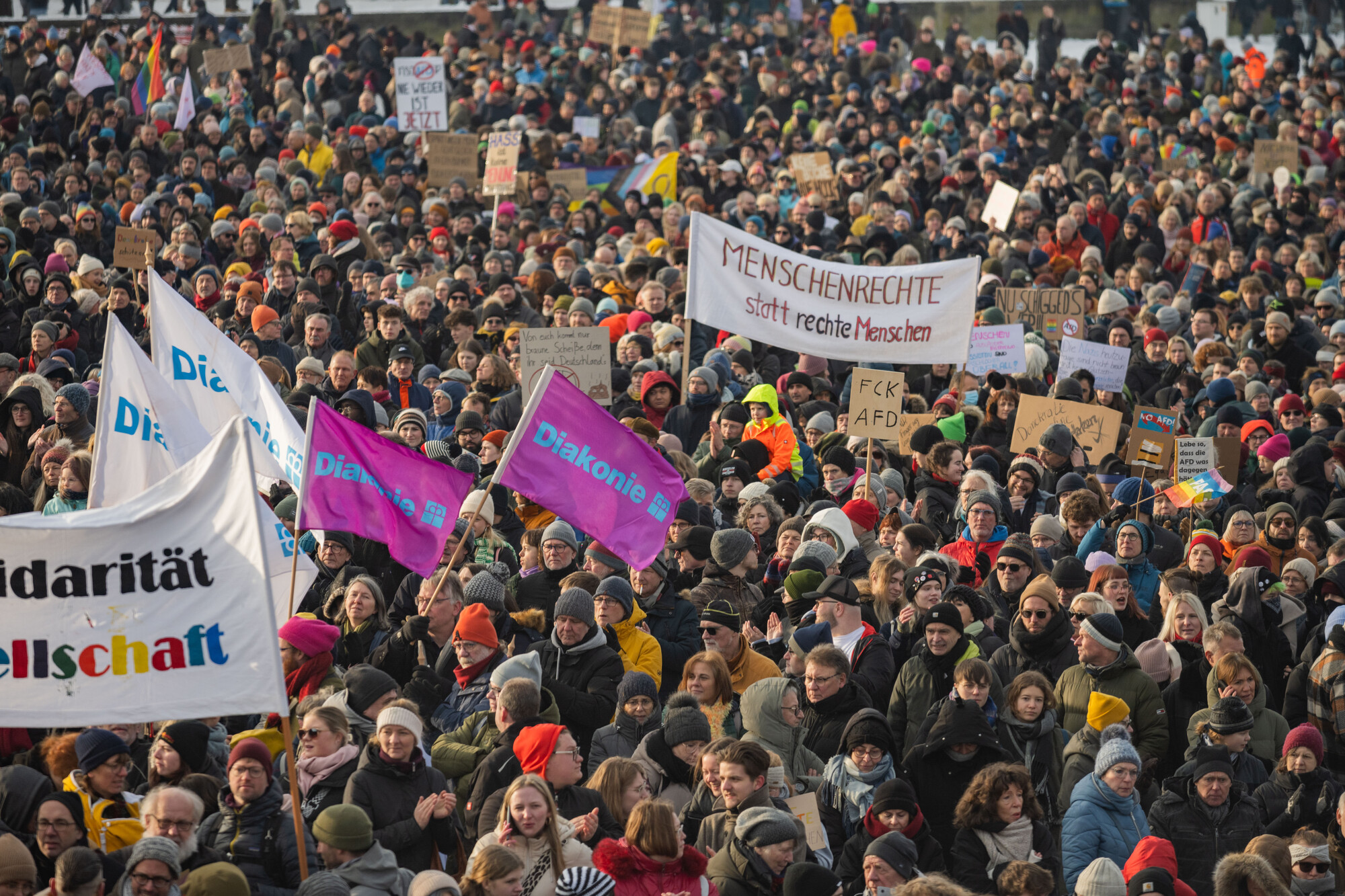 Blick von oben auf eine demonstrierende Menschenmasse. Man erkennt Banner mit der Aufschrift "Diakonie" und "Menschenrechte statt rechte Menschen"
