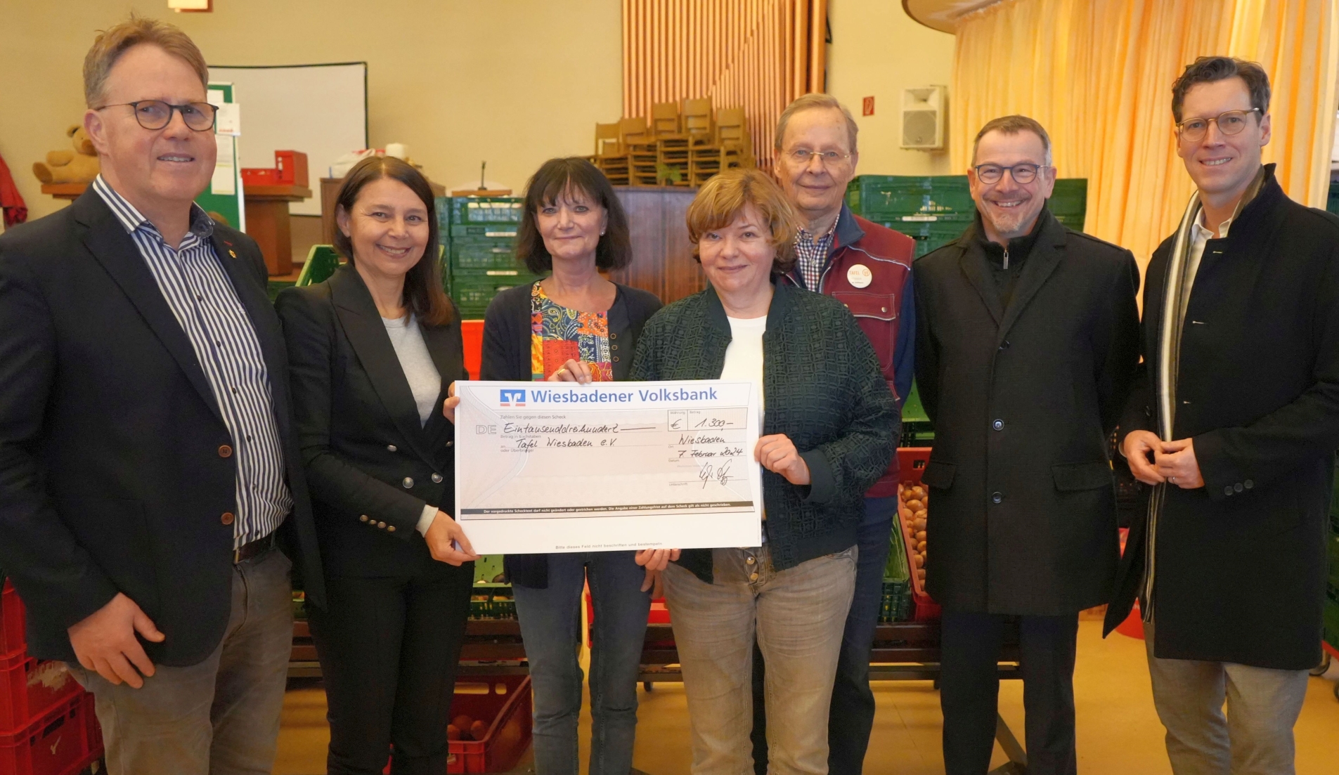 Polizeipfarrer Dr. Michael Grimm übergibt einen großen Scheck an die Verantwortlichen der Tafel. Insgesamt sieben Personen lächeln in die Kamera.