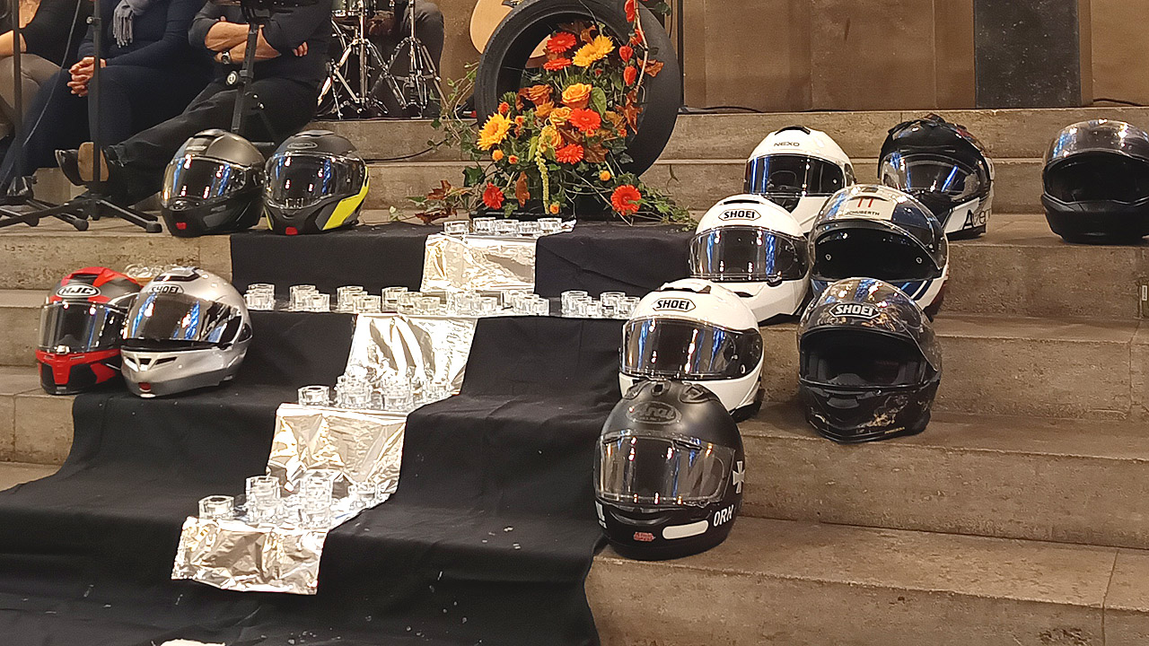 Gedenken an verunglückte Motorradfahrerinnen und Motorradfahrer Kreuz aus Teelichtern gelegt, daneben die Motorradhelme der verstorbenen Motorradfahrer