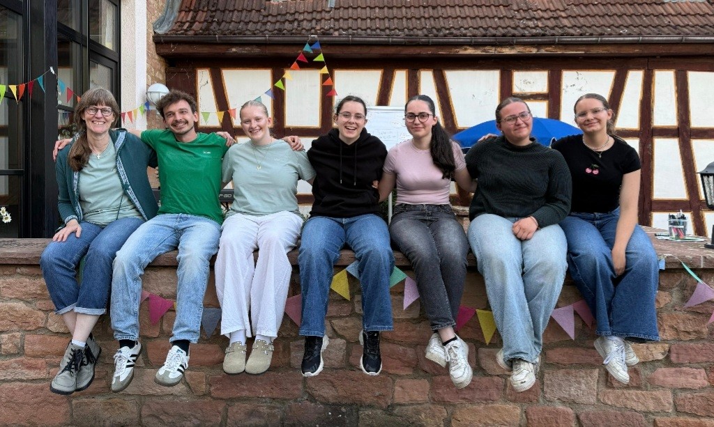 Das Bild zeigt mehrere Personen, die auf einer Mauer sitzen.