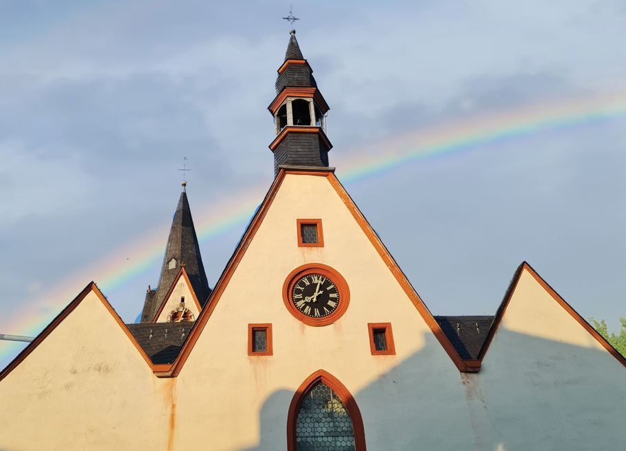 Das Bild zeigt die Kirche in Babenhausen über der ein Regenbogen leuchtet.