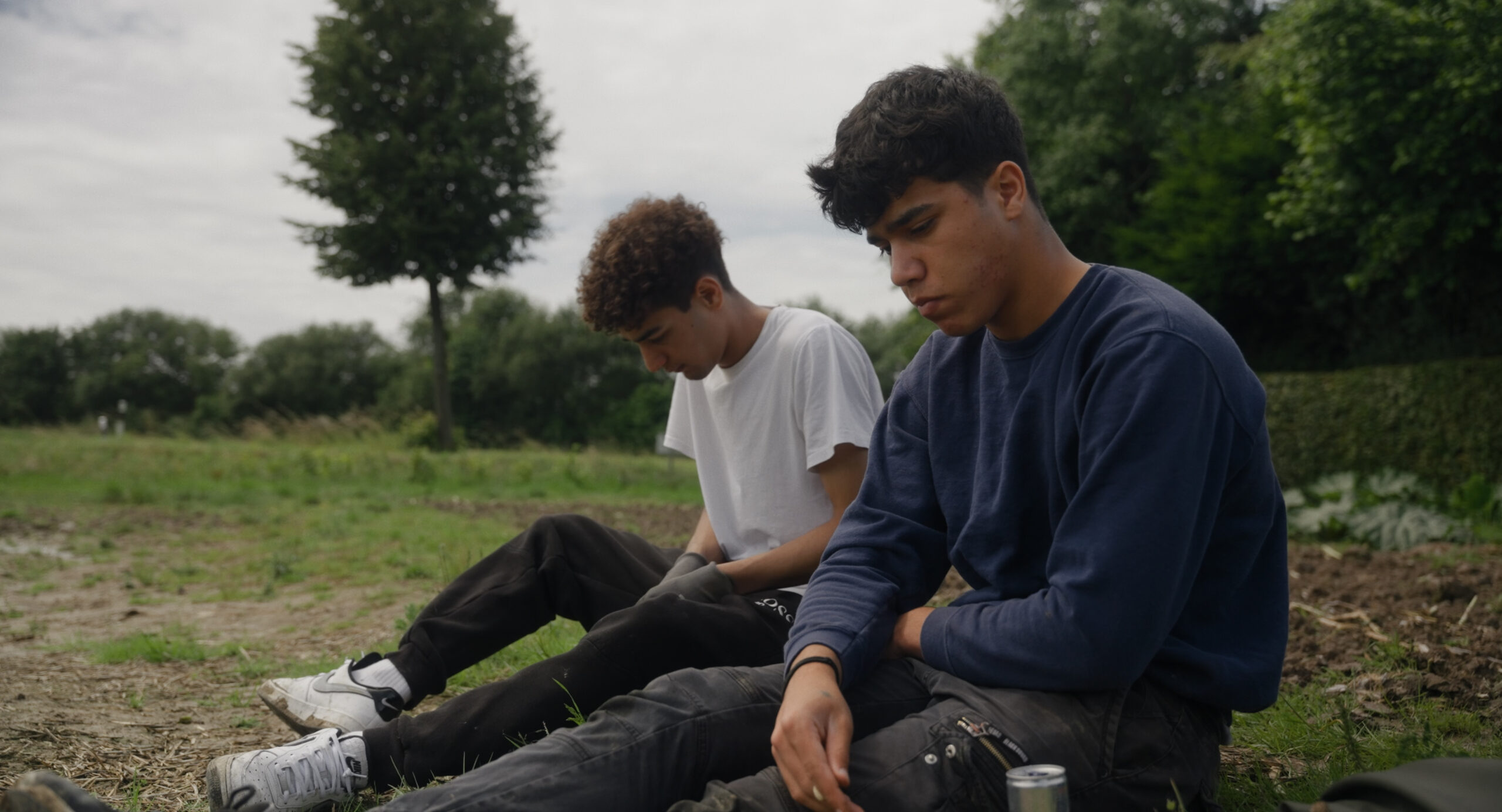 Wohin mit mir? – Dokumentarfilm Zwei junge Männer sitzen mit gesenkten Köpfen auf dem Gras