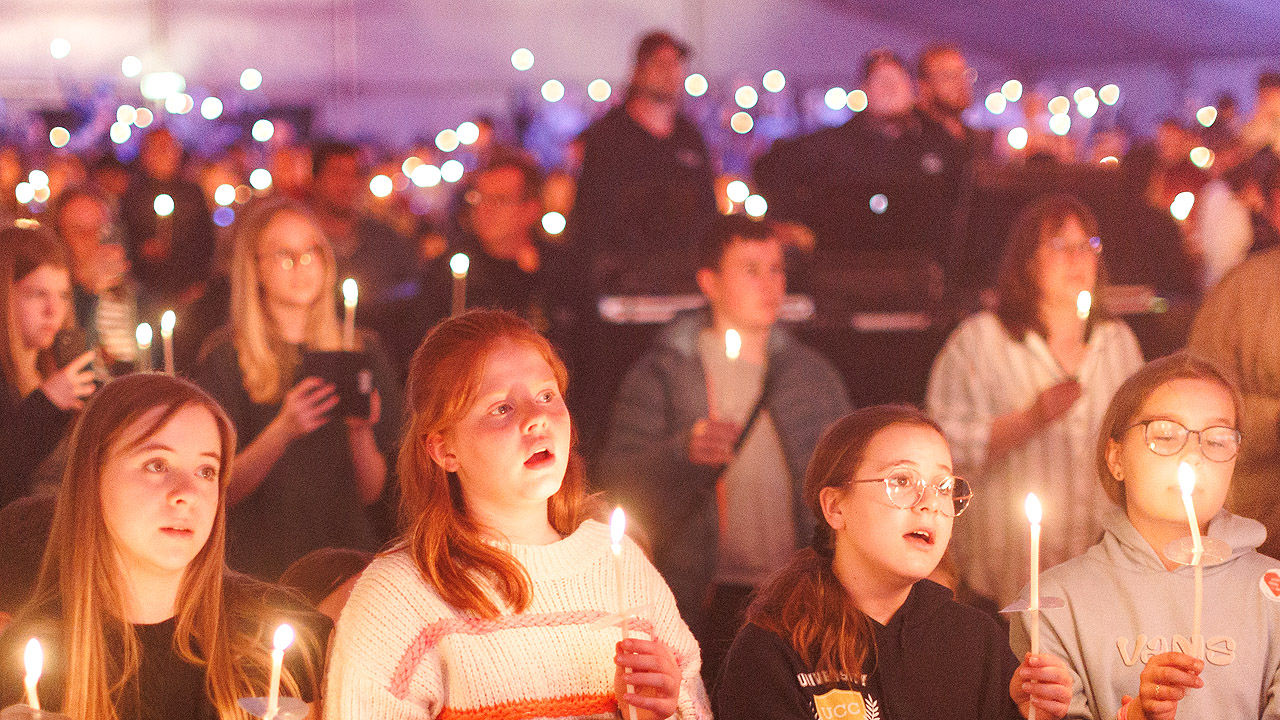 Viele Jugendliche halten Kerzen in der Hand bei gedimmten Licht