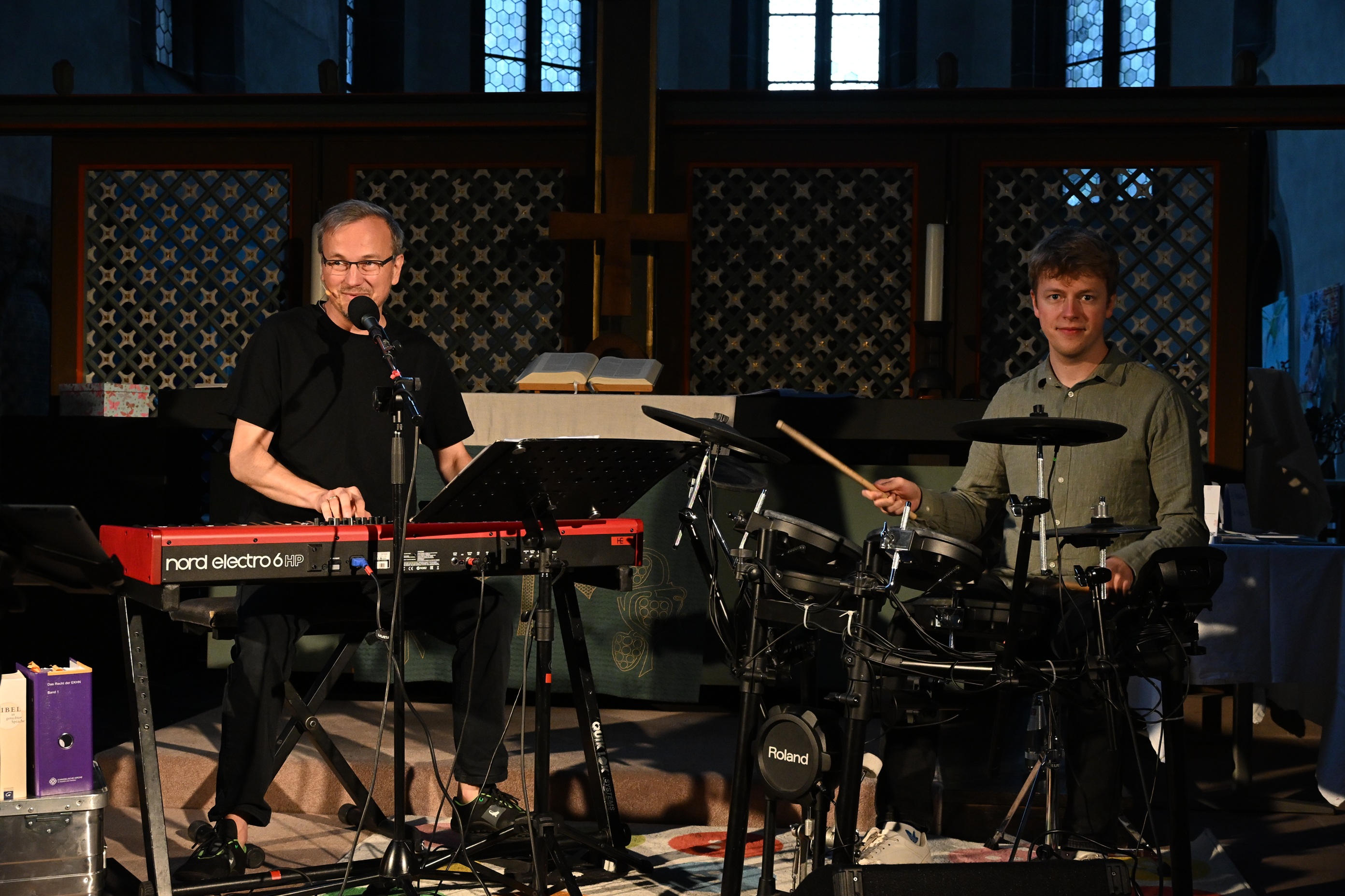 Mann am Klavier und Mann am Schlagzeug vor Lettner.