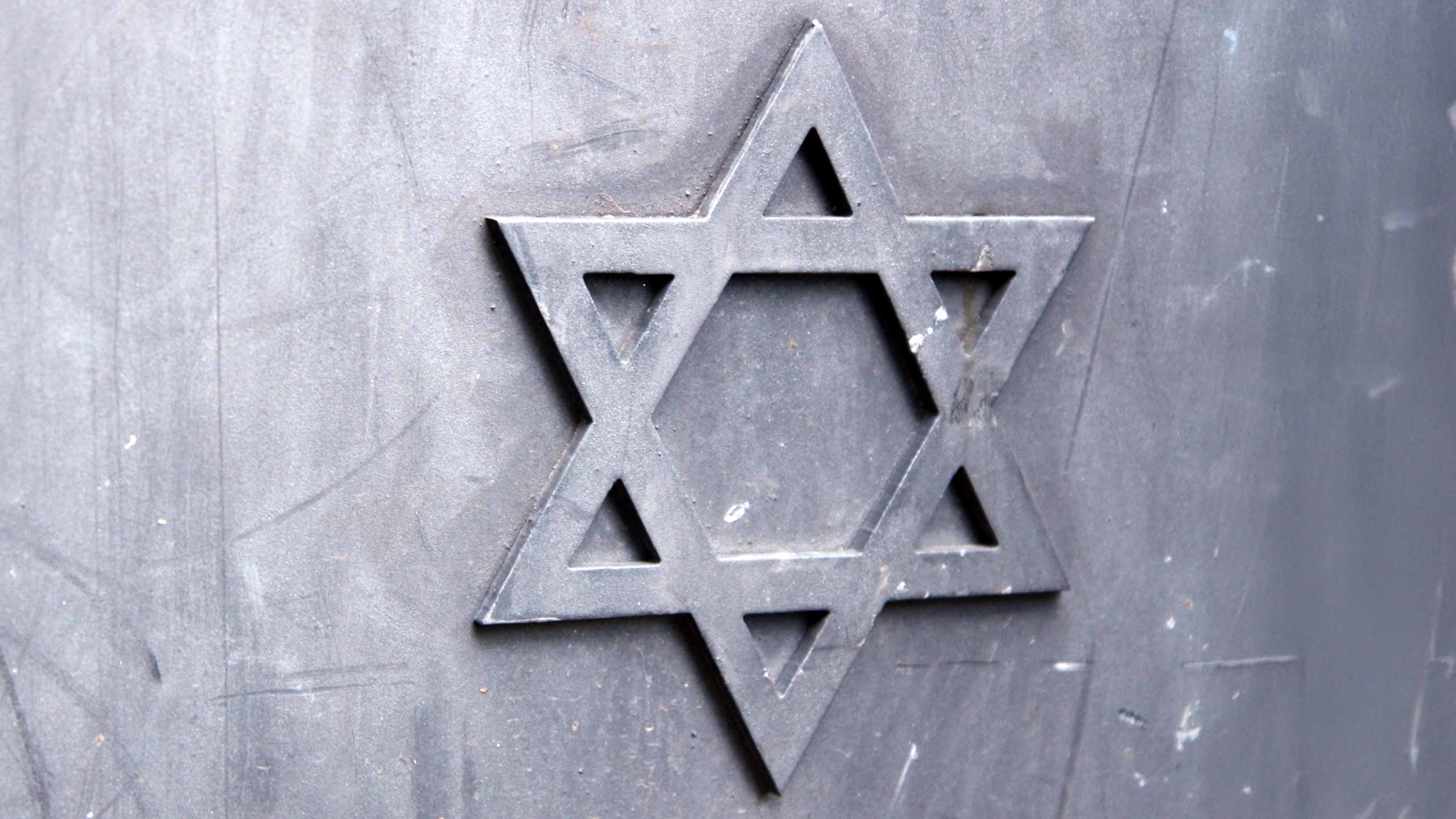 Ein Davidstern als Metallsymbol ist auf einer grauen Metallfläche befestigt.