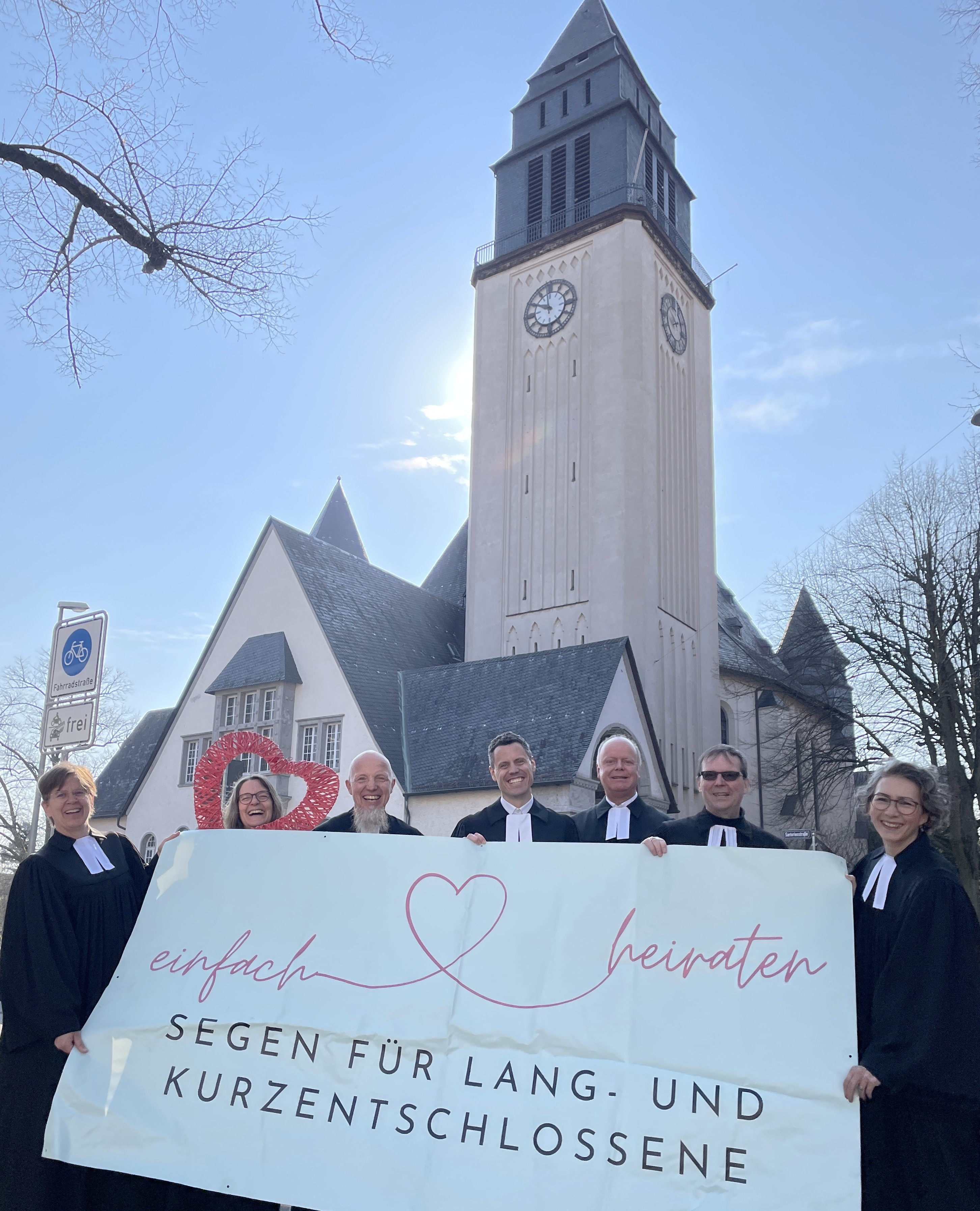 Pfarrer vor der Kirche mit Banner in der Hand