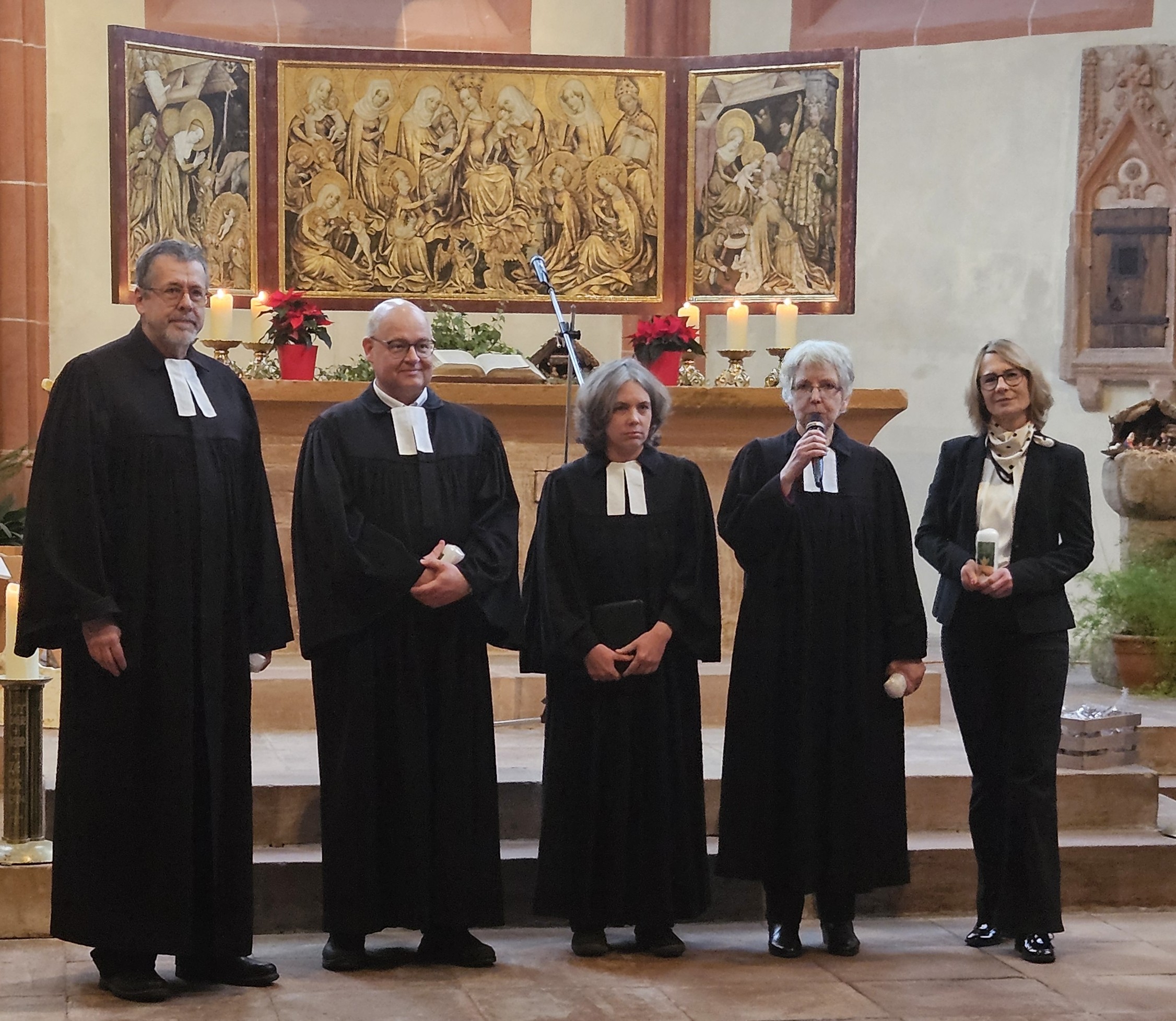 Pfarrer Jürgen Füg, Pfarrer Alexander Wohlfahrt, Pfarrerin Daniela Wiegers, Pfarrerin Regine Jünger und Marion Gengel-Knapp stehen in Talaren (Marion Gengel-Knapp im schwarzen Hosenanzug) vor dem Altar in der Ortenberger Marienkirche. Regine Jünger hält ein Mikrofon in der Hand.