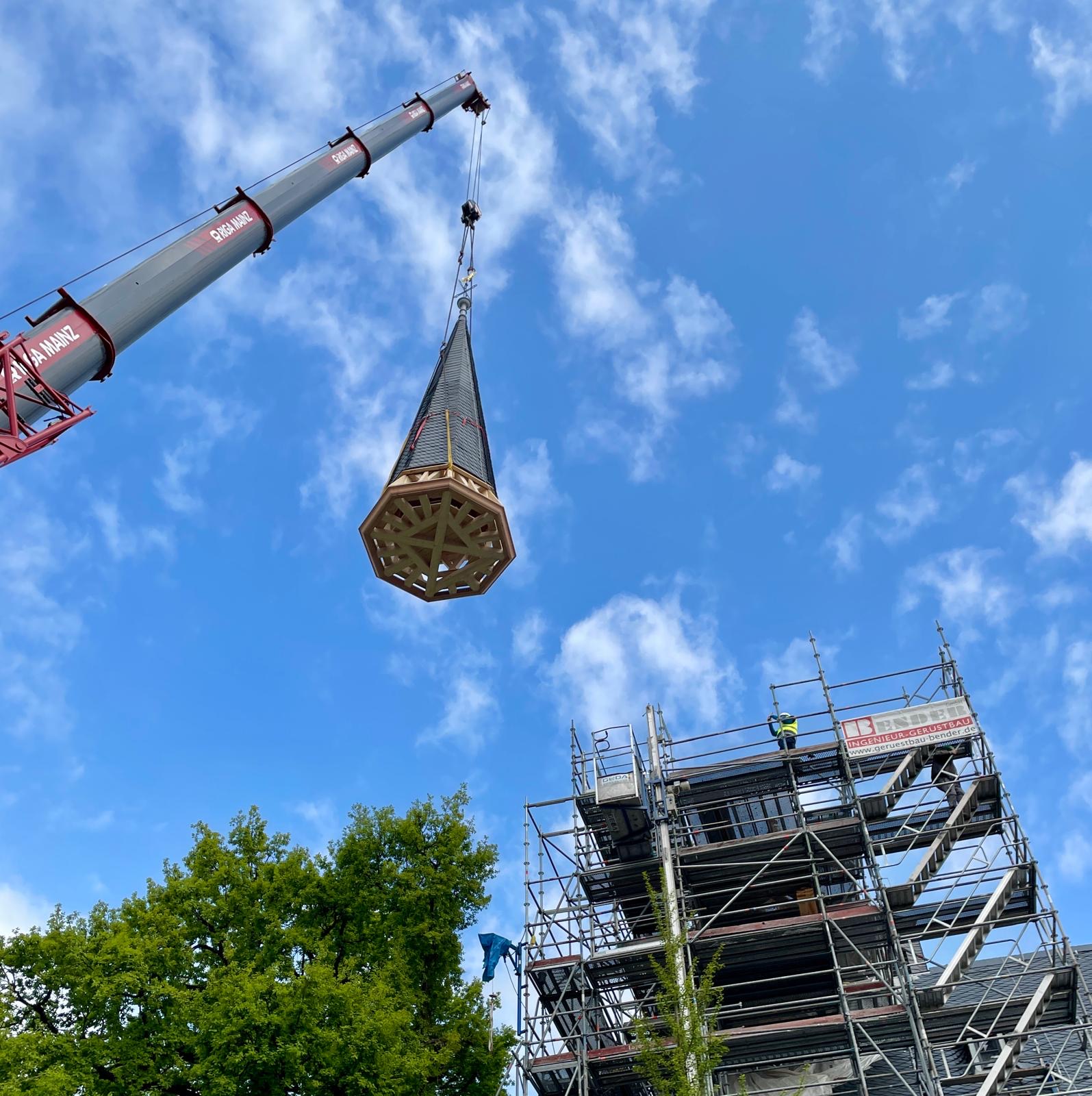 Der frisch sanierten Dotzheimer Kirchturm schwebt in der Luft zurück auf das Dach.