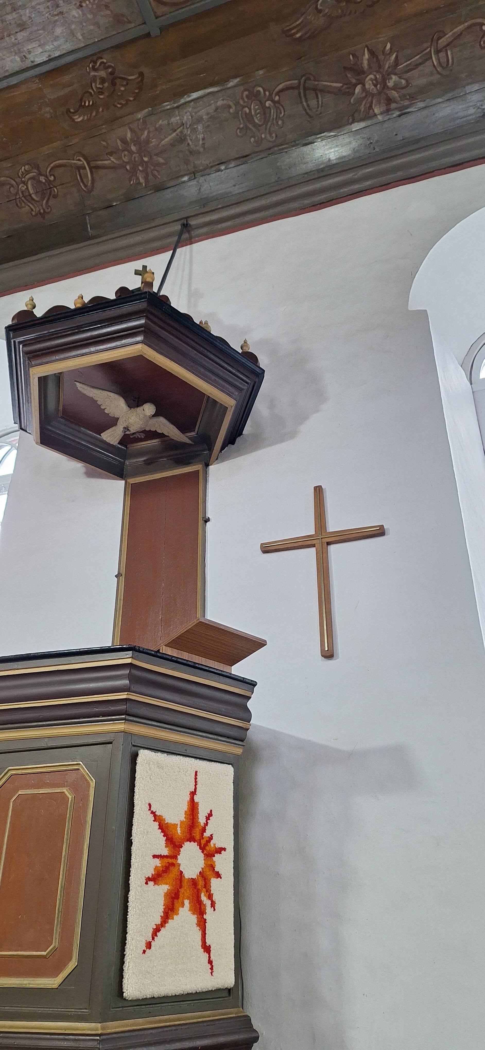 Holzkreuz an der Wand neben der Kanzel