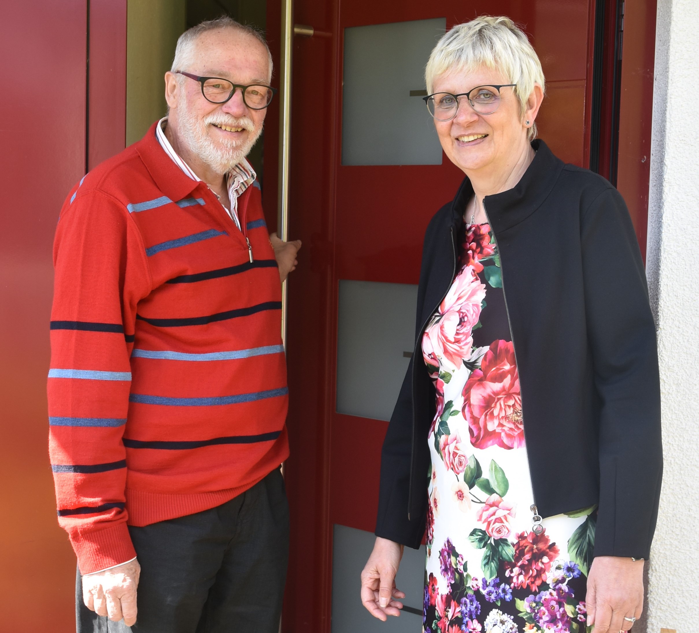 Udo und Silvia Heuermann stehen vor der roten Haustür des Schottener Pfarrhauses.
