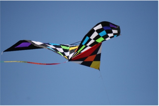 Ein großer, bunter Drache ein einer Leine fliegt in der Luft