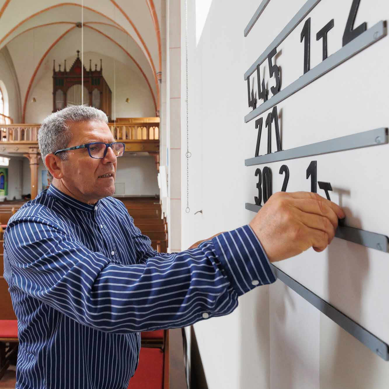 Küster bringt Liednummern an