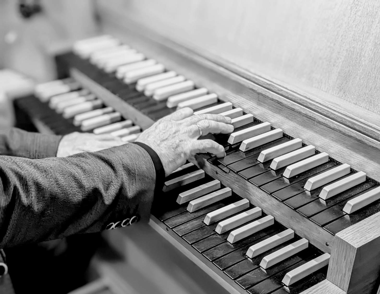Zwei Hände spielen auf einer Orgel.