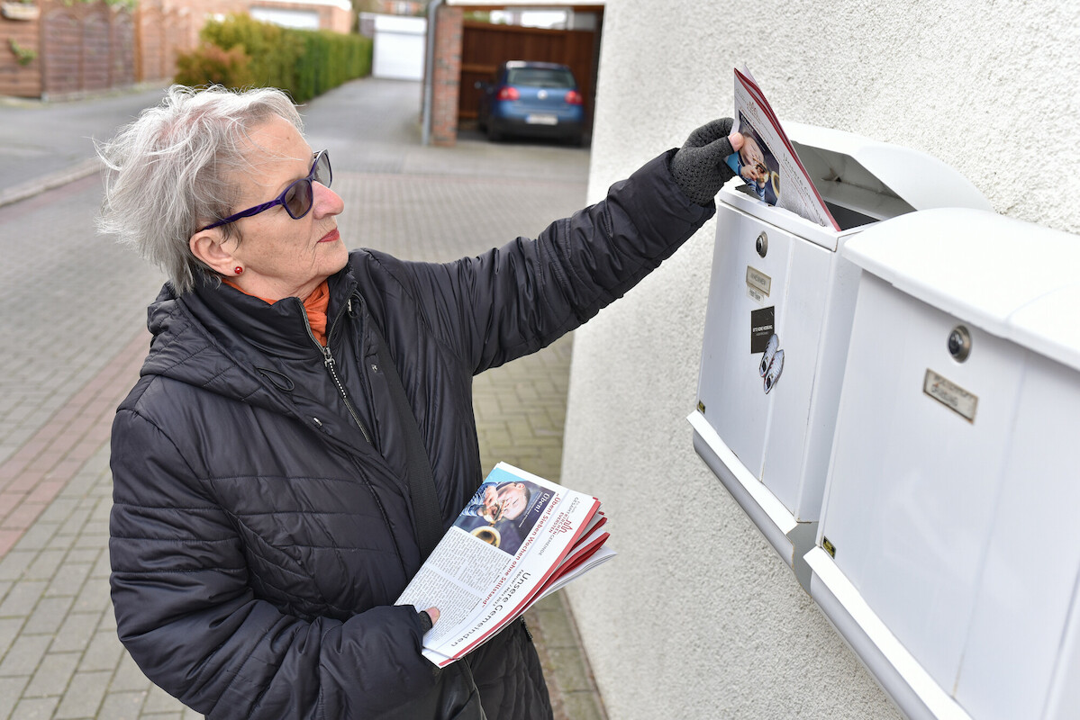 Ehrenamtliche Redaktion verteilt Zeitschrift in Briefkasten 3 Eine Frau verteilt die fertige Zeitschrift "Unsere Gemeinde" in Briefkästen.