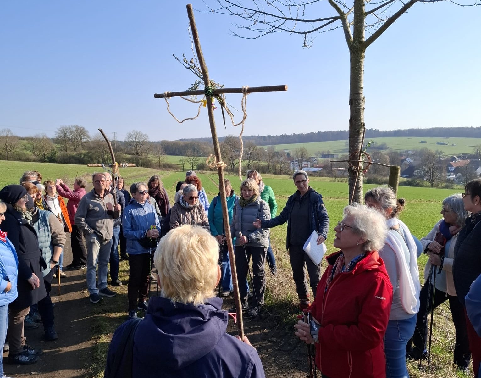 Pilgern zur Passion Menschengruppe im Freien mit einem Holzkreuz aus Zweigen