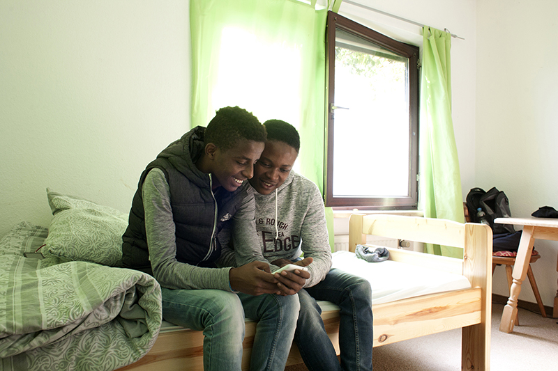 Zwei Jugendliche sitzen auf einem Bett in einer diakonischen Einrichtung