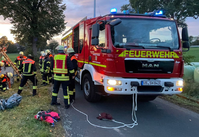 Mehrere Feuerwehrleute des Amtes für Gefahrenabwehr stehen neben einem Feuerwehrfahrzeug im Einsatzbereich. Das Fahrzeug ist von der Seite sichtbar.