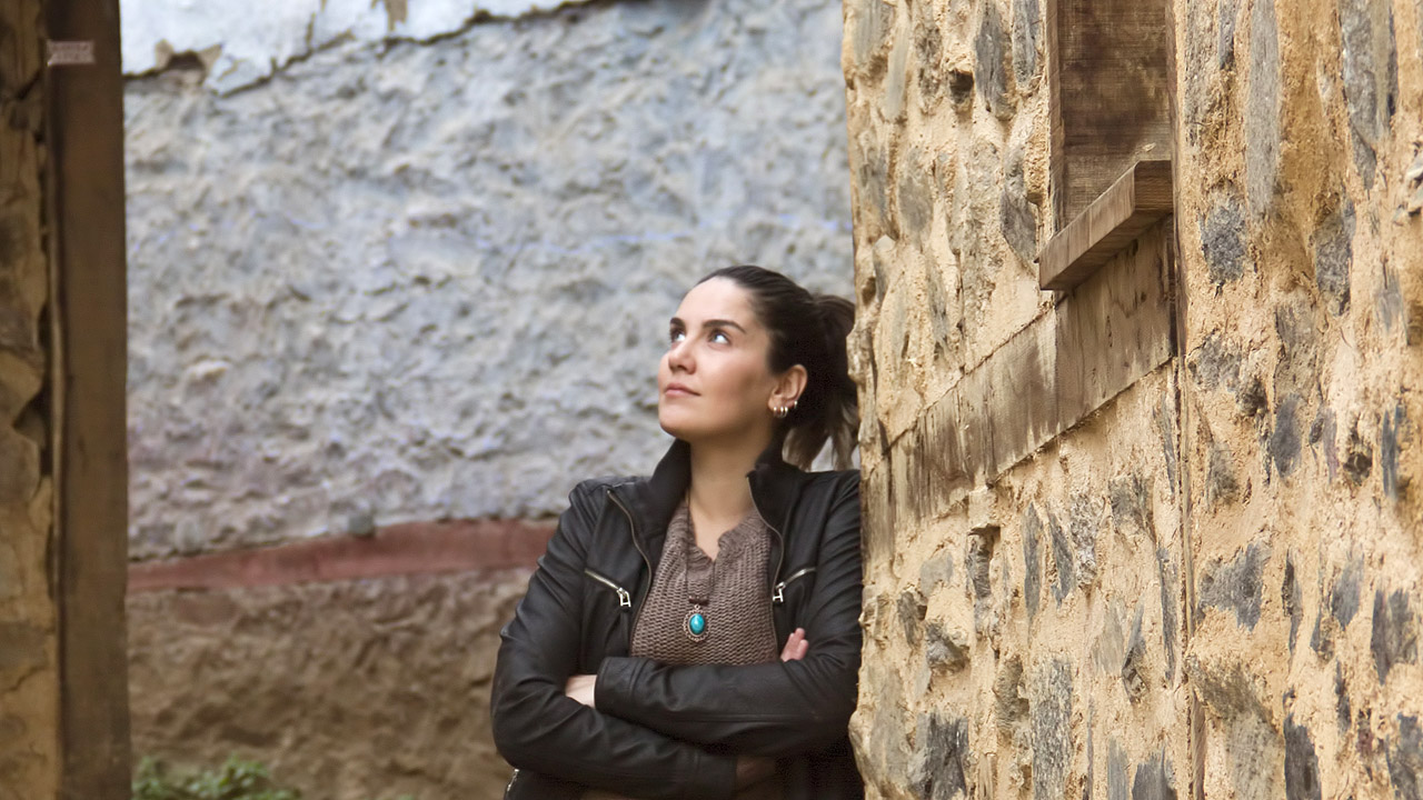 Eine Frau blickt nach oben, sie steht zwischen dicken Mauern