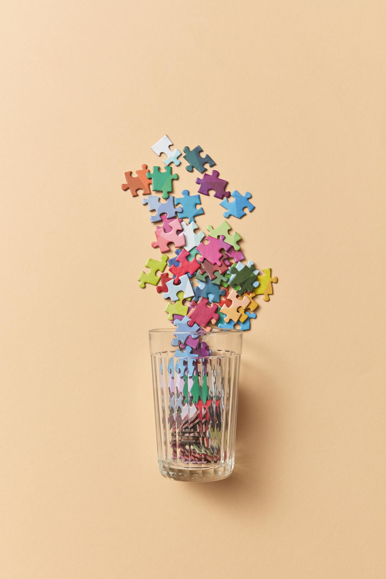 Viele Puzzleteile fallen in ein Glas