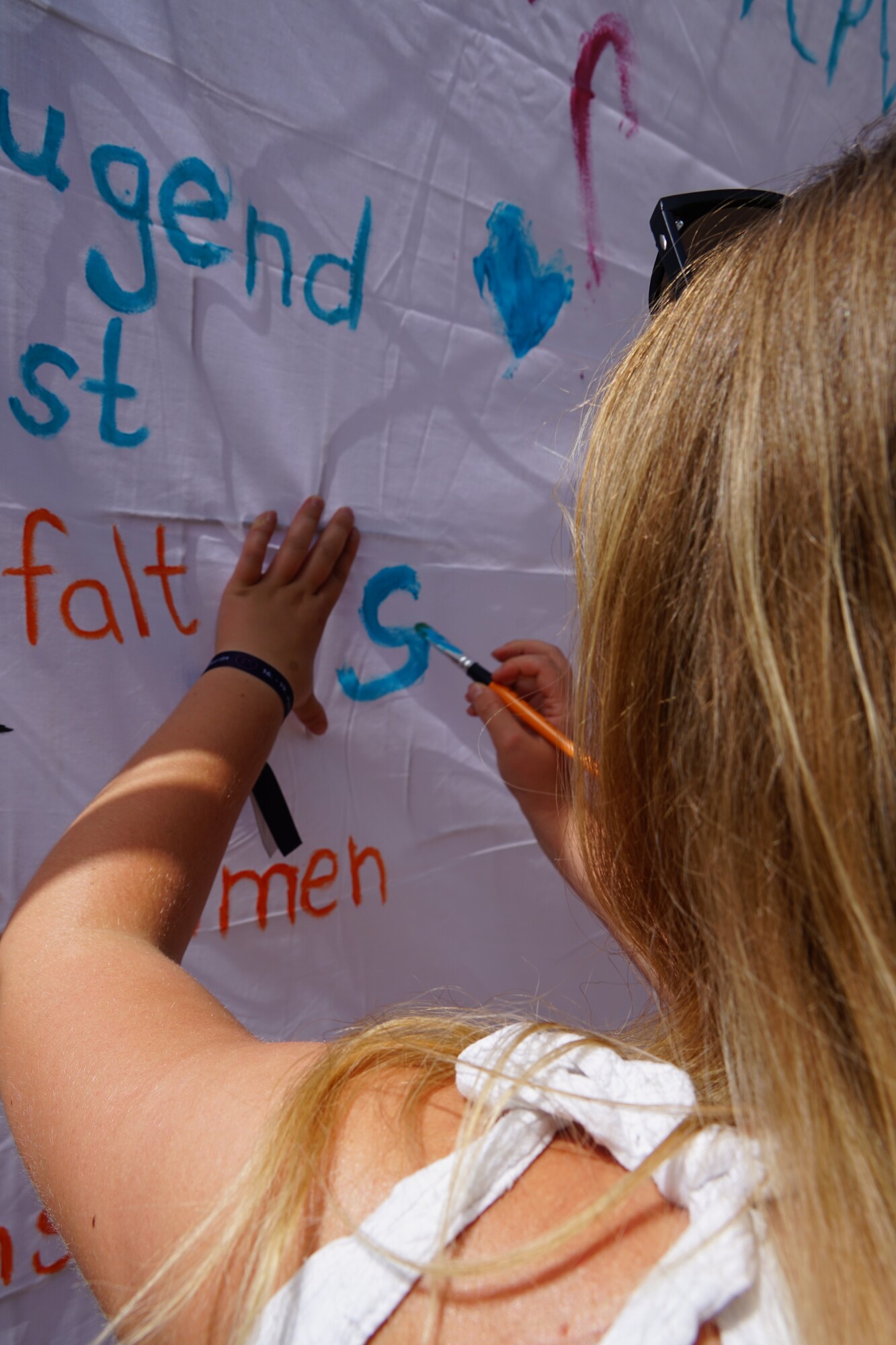 Junge Frau, man sieht nur einen Teil ihres Hinterkopfs und ihren linken Arm, schreibt mit bunten Stiften Worte auf eine Flip Chart