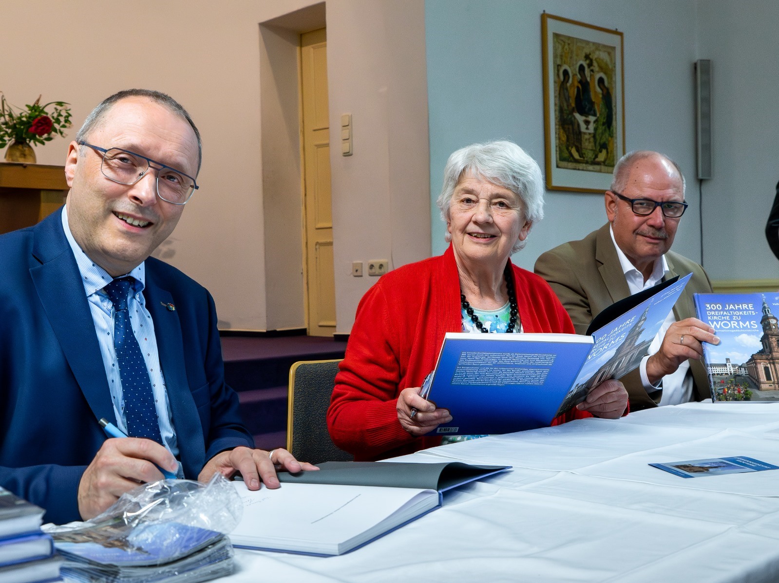 Pfarrer Volker Johannes Fey, Dr. Irene Spille und der Wormser Oberbürgermeister Adolf Kessel (von links) beim Signieren des Buches