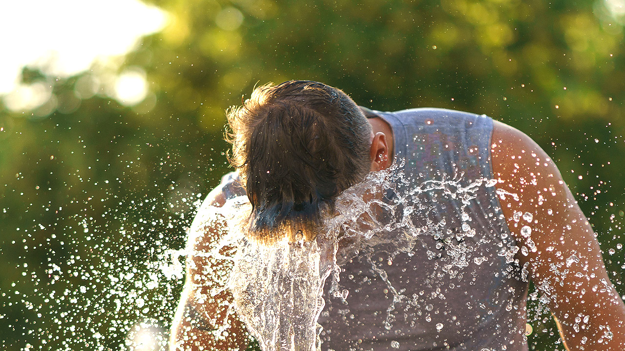 Hitze Ein Mann kühlt sich an einem Springbrunnen ab