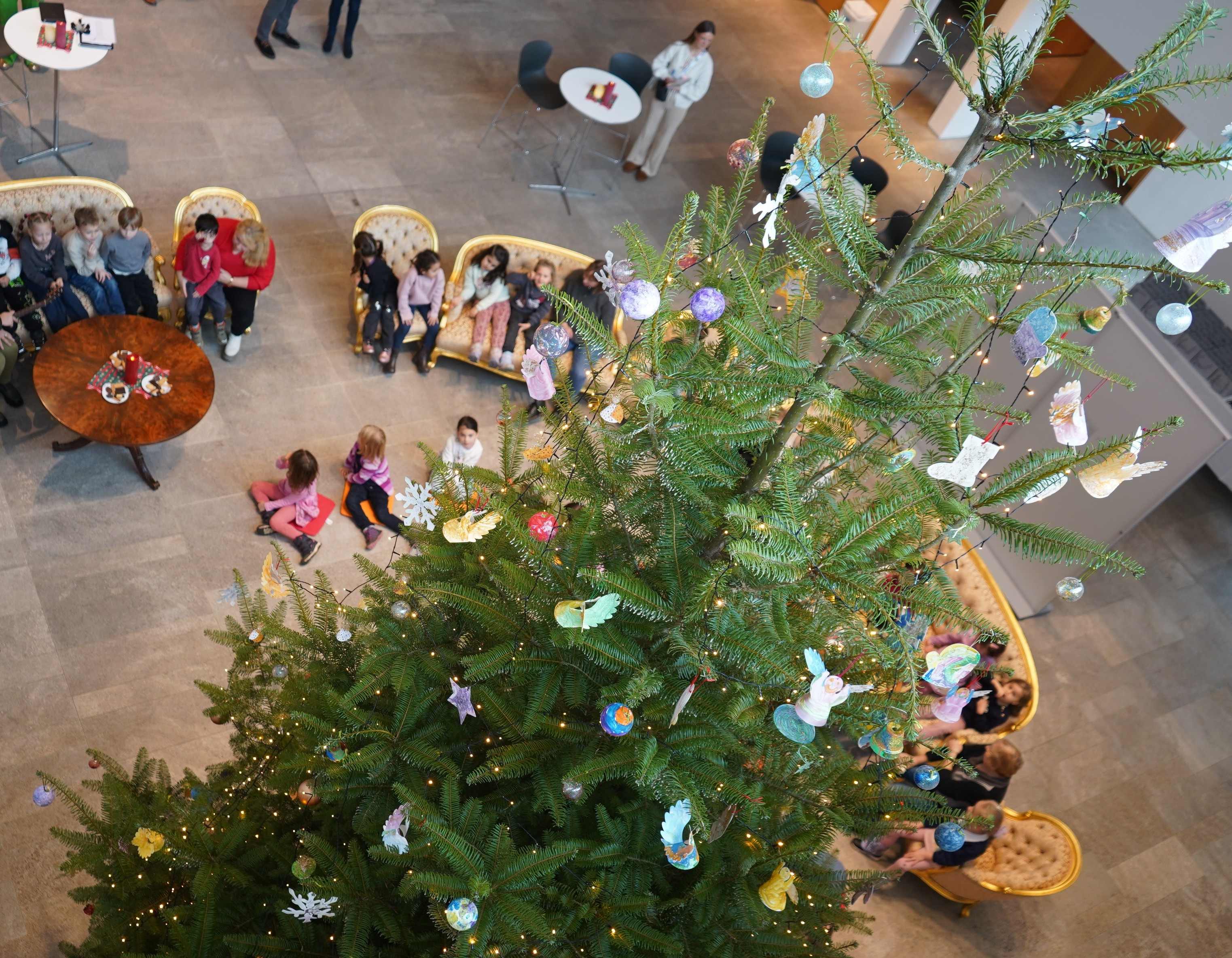 Kinder im Foyer des Landtags sitzen um einen gescmückten Weihnachtsbaum
