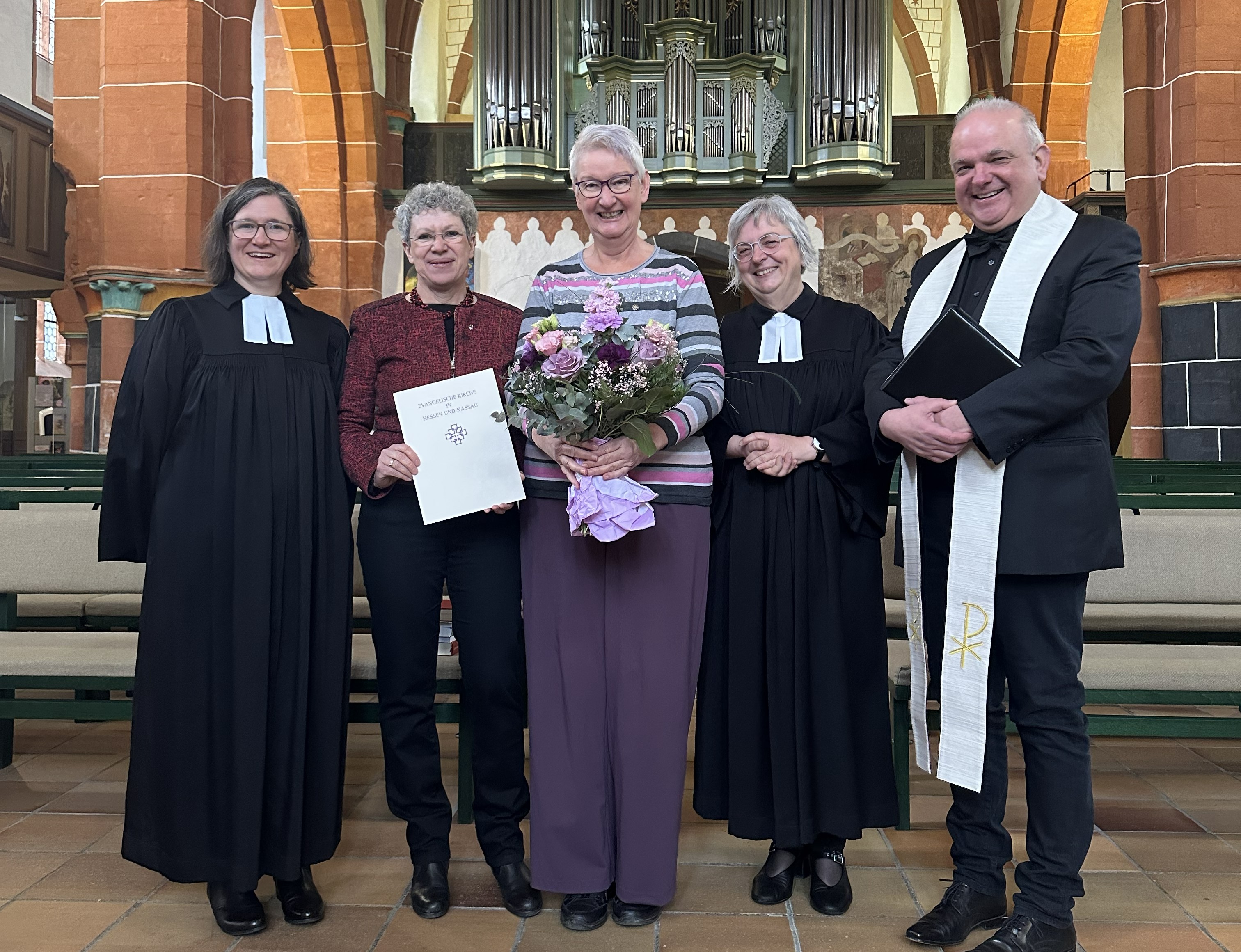 Fünf Personen stehen nebeneinander vor dem Altar der Walpurgiskirche. In der Mitte steht Sylvia Bräuning als Geehrte. Neben ihr stehen weitere leitende Vertreterinnen und Vertreter des Dekanats: links die stellvertretende Dekanin Luise Berroth und Birgit Pfeiffer, rechts Dekanin Dr. Dorette Seibert sowie der neue Präses Martin Reibeling. Alle sind einander zugewandt und bilden eine Gruppe rund um die Ausgezeichnete.