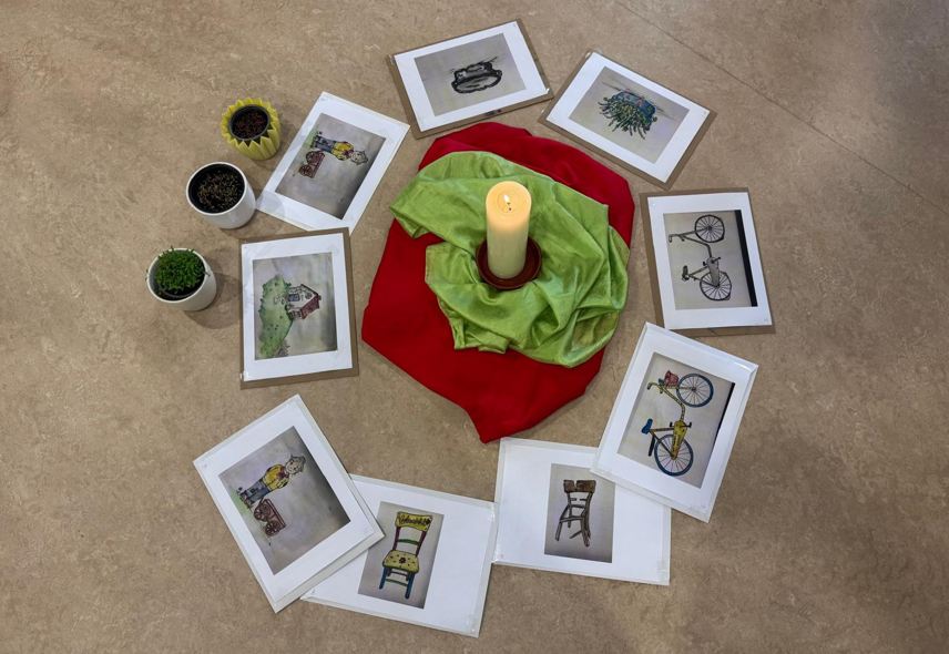 Das Bild zeigt eine Kerze um die verschiedene Fotos liegen.