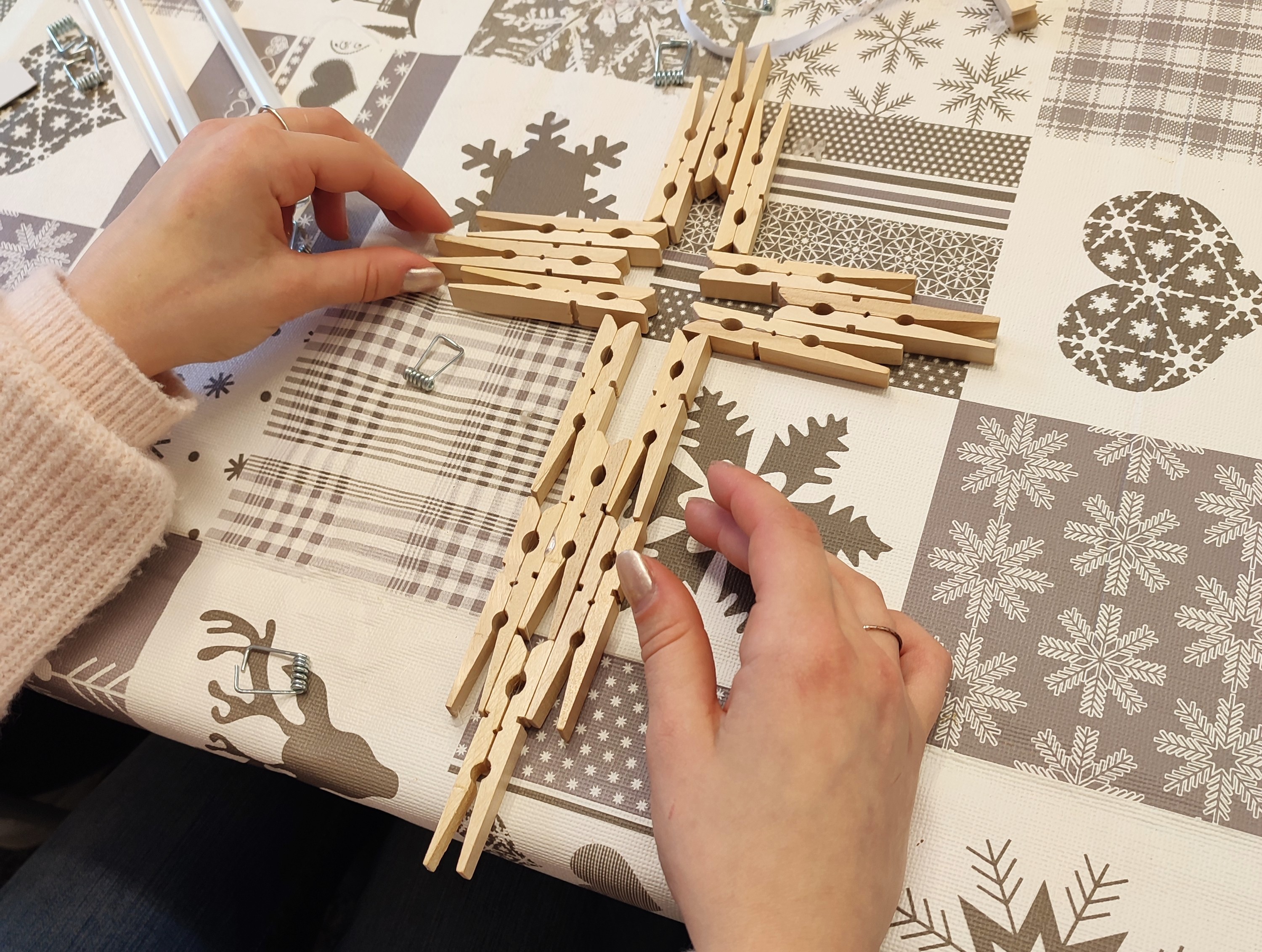 Ein Mädchen hat ein Kreuz aus Wäscheklammern gebastelt.