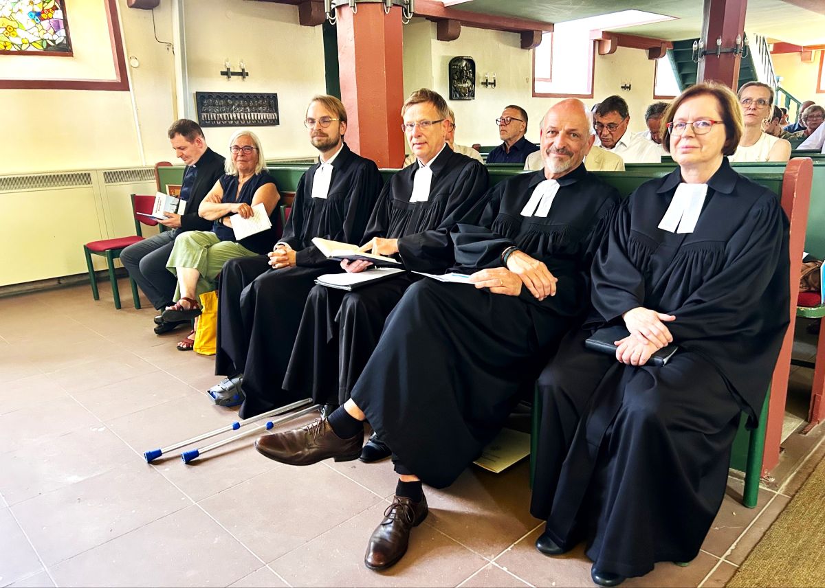 Abschiedsgottesdienst von Andreas Lipsch Vier Pfarrer*innen mit Talaren sitzen in der ersten Kirchenbank