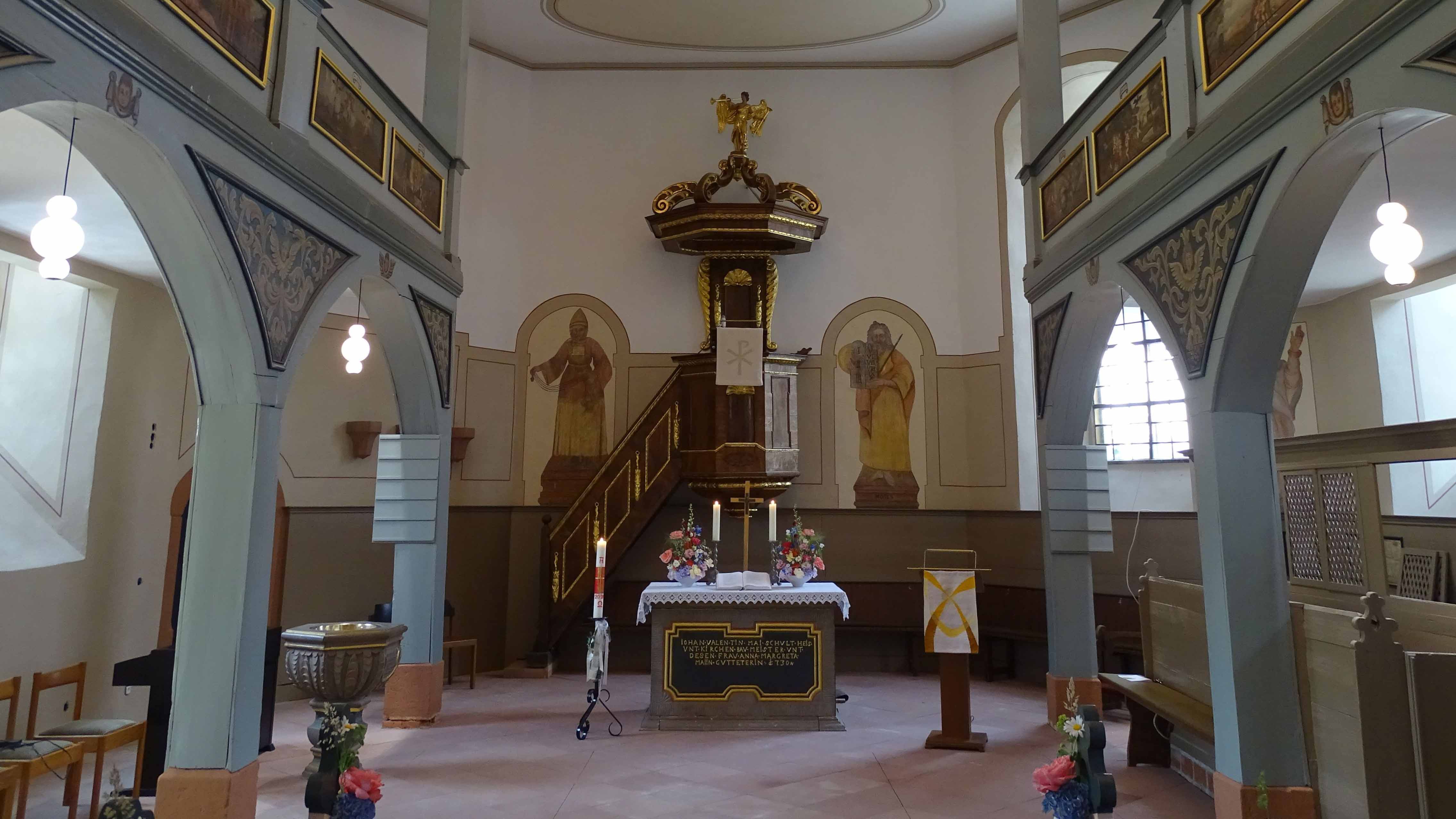 Evang_Kirche_Hähnlein_Juni_2026_C_Günther_Ahlheim_1_16zu9.jpg Der Blick führt durch das Kirchenschiff auf den Altar in der Mitte. Dahinter befindet sich eine erhöhte Kanzel mit Treppenaufgang. Links vorne steht ein Taufbecken. Helle Rundbögen tragen die seitlichen Emporen, an deren Brüstungen mehrere Bilder angebracht sind. Kerzen, Blumen und Kirchenbänke vervollständigen die schlichte Innenausstattung.