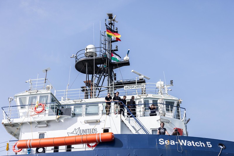 Blau-weißes Seenotrettungschiff mit der Besatzung auf der Reeling. 