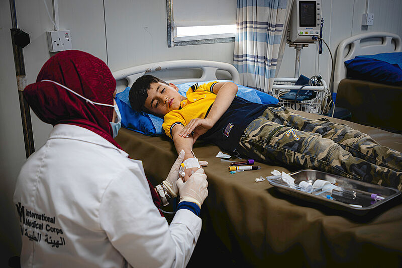 Flüchtlingscamp Zaatari Krankenhausbett Krankenhaus in Zaatari, ein Junge liegt im Bett, die Mutter sitzt vor dem Bett und hält seine Hand