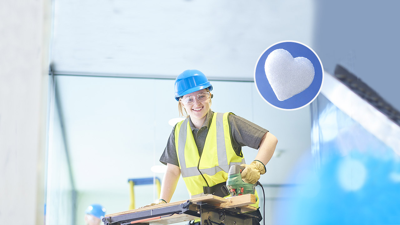 Eine junge Frau mit Helm in der Tischlerlehre