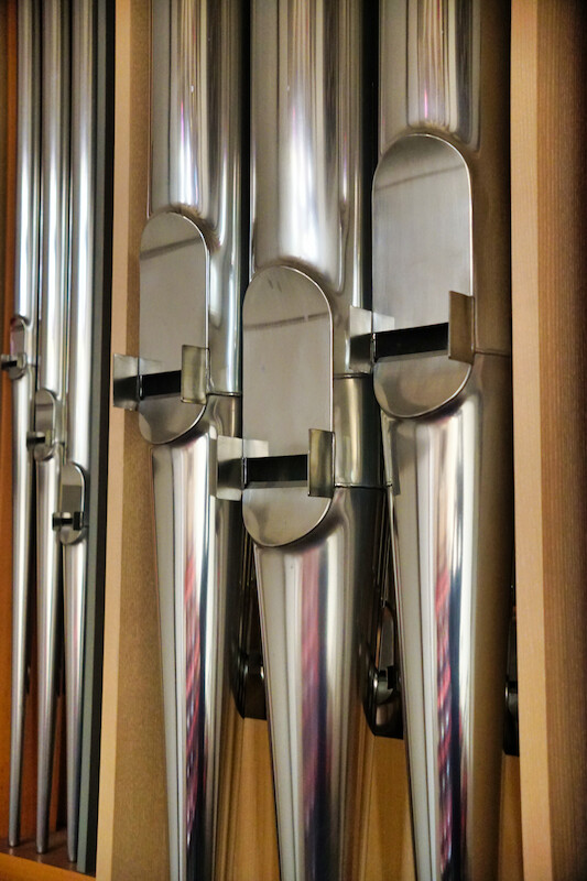 Detailaufnahme einer Kirchenorgel mit Blick auf die Orgelpfeifen. Seitlich aufgenommen im Hochformat.