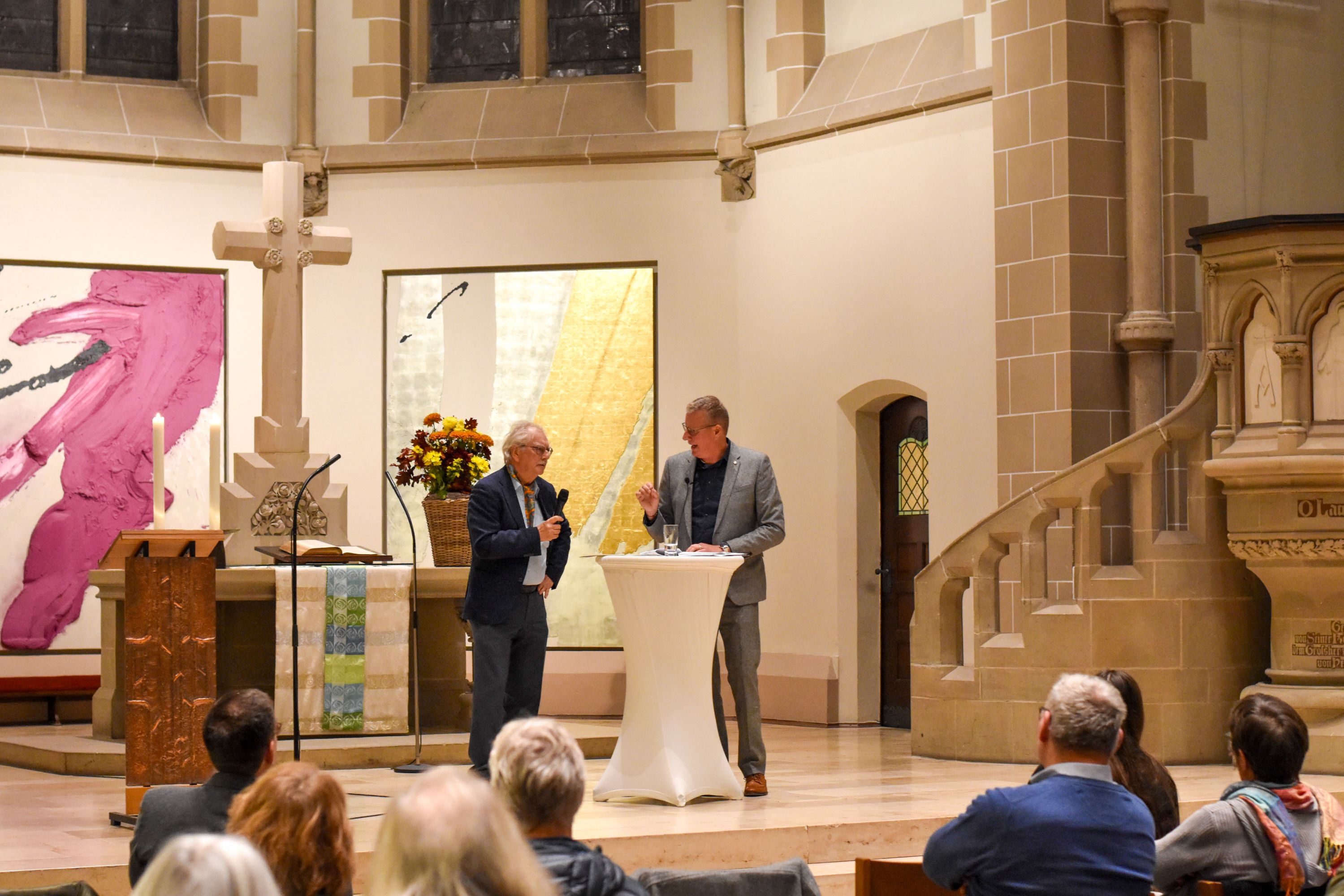 Zwei Männer an einem Stehtisch im Altarraum einer Kirche.
