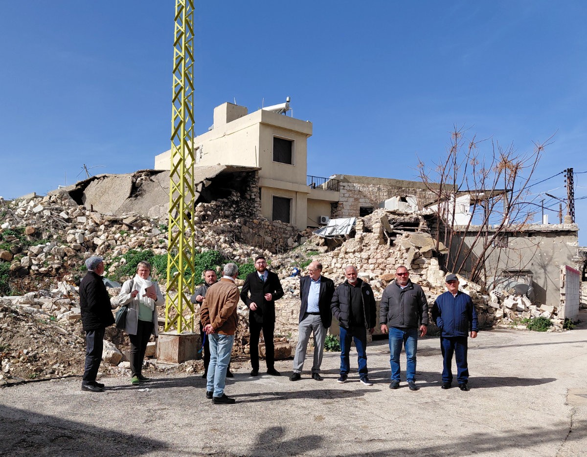 Zerstörte Kirche, davor eine Gruppe von Personen.