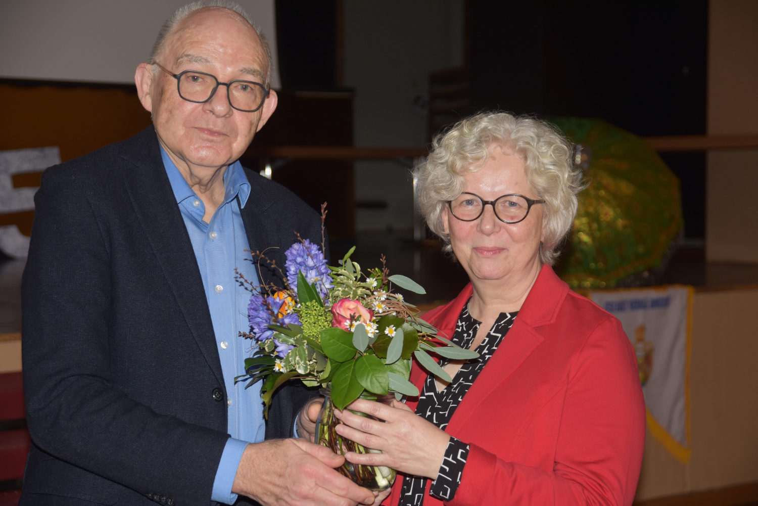 Präses Rolf Hartmann überreicht Rita Stoll einen Strauß Blumen.