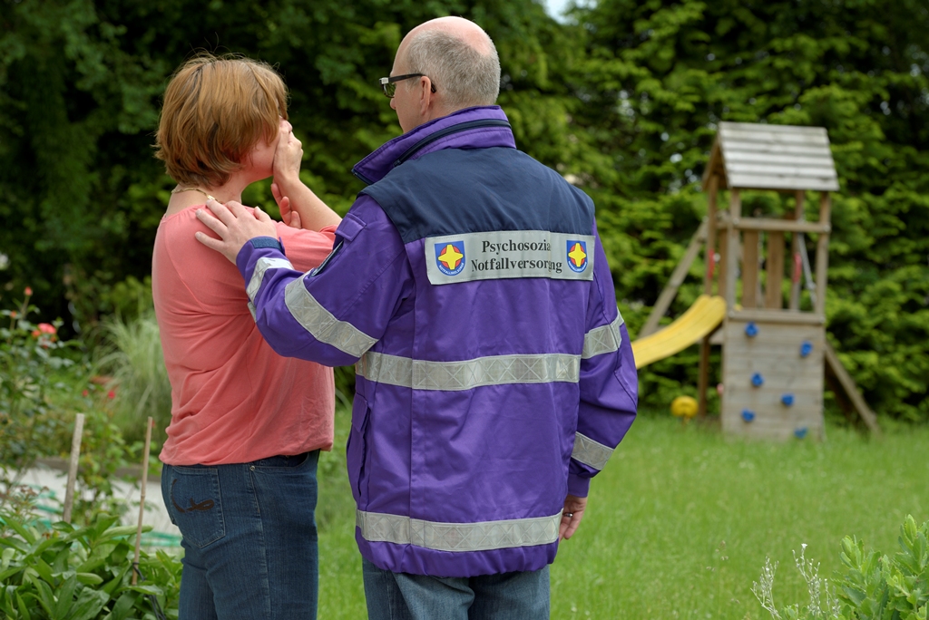 Betroffene hält sich Hand vor den Mund. Notfallseelsorger tröstet.
