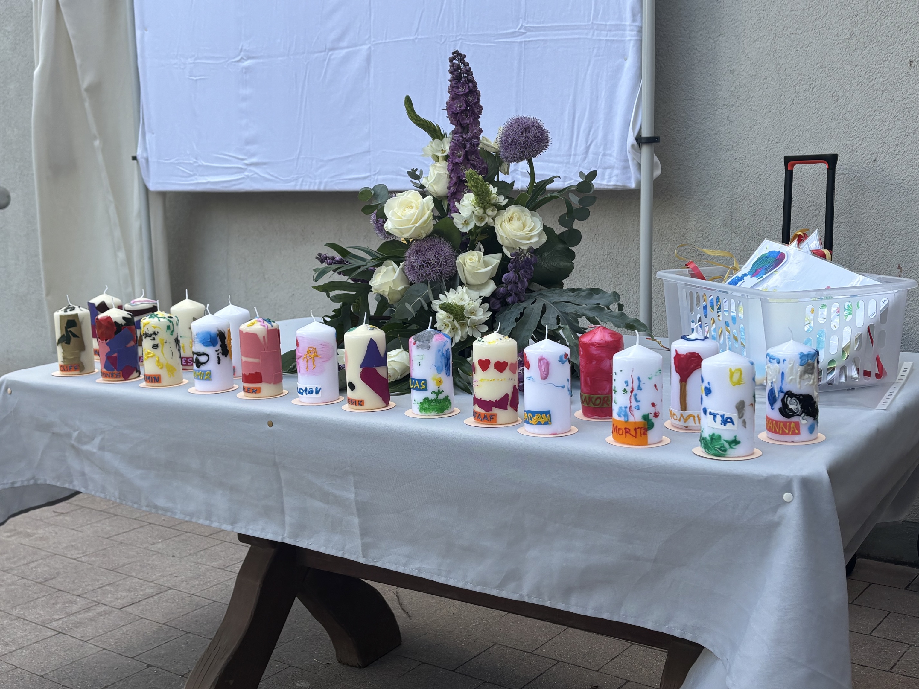 selbstdekorierte weiße Kerzen stehen auf einem Tisch mit einer weißen Tischdecke. Als Abschiedsgeschenk der Wackelzahn-Kinder