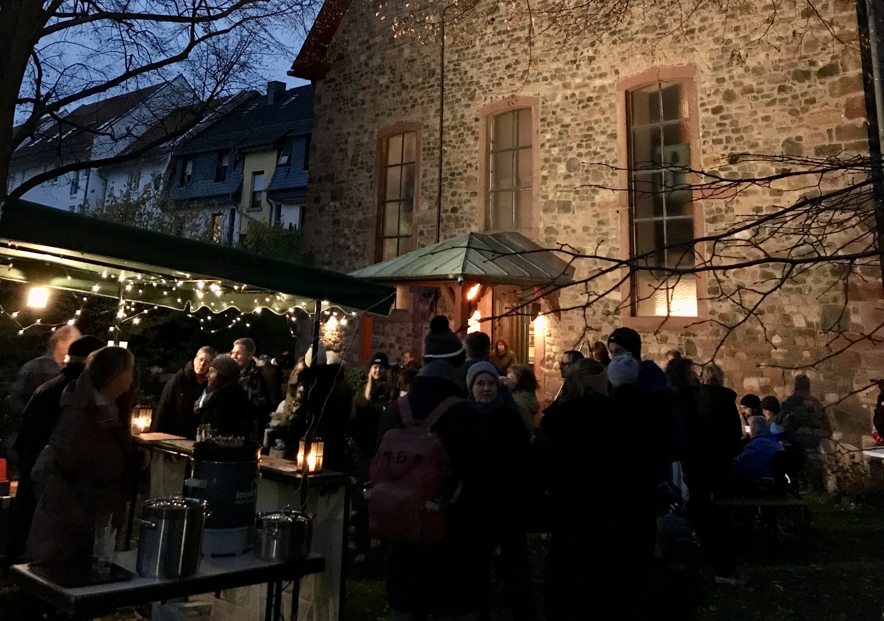 Praunheimer Adventsmarkt vor der Auferstehungskirche Blick auf den Platz im Kirchgarten vor dem Eingang der Auferstehungskirche, weihnachtlich festlich beleuchtet