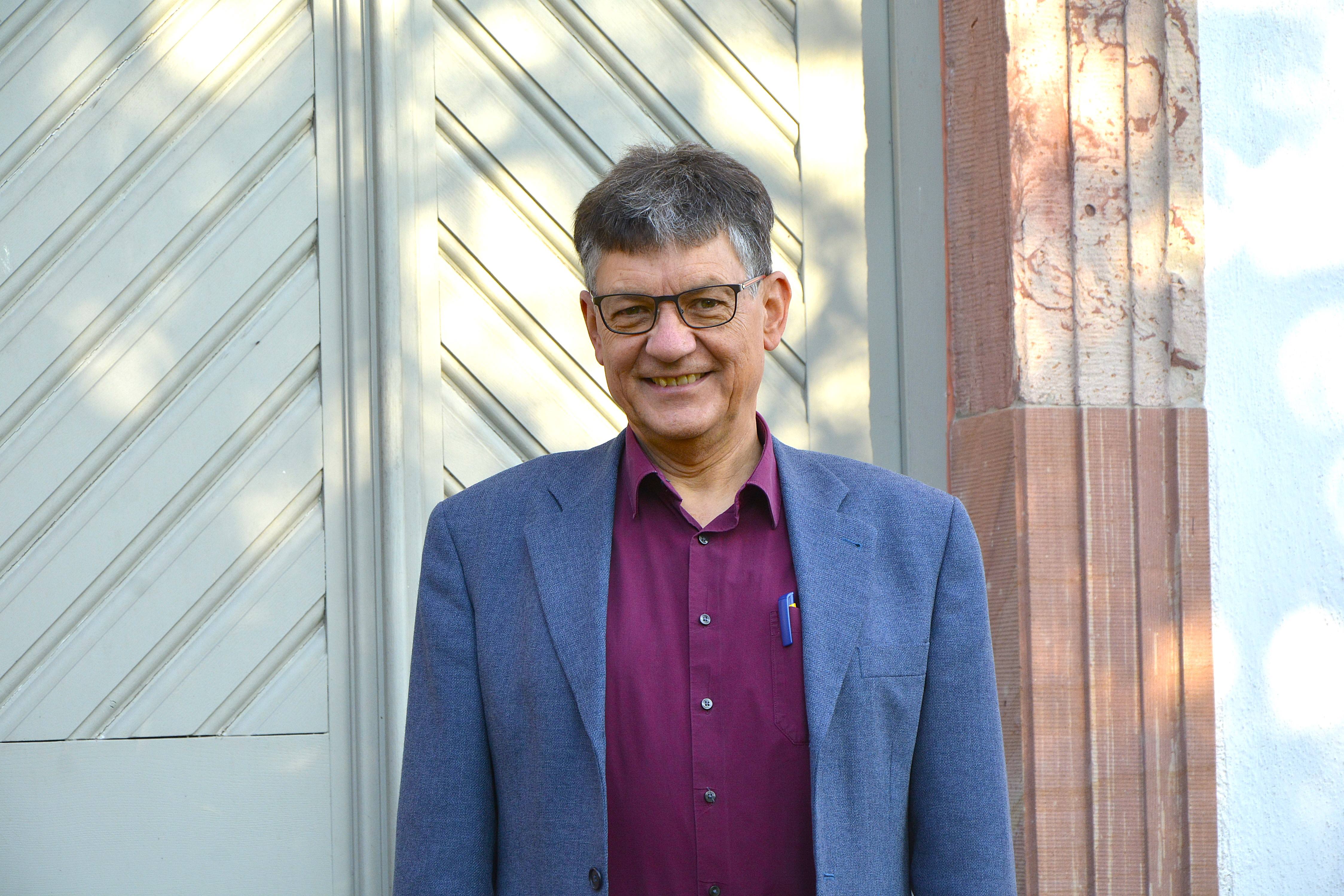 Pfarrer Johannes Seemann vor der grauen Tür der Pfarrkirche in Heftrich