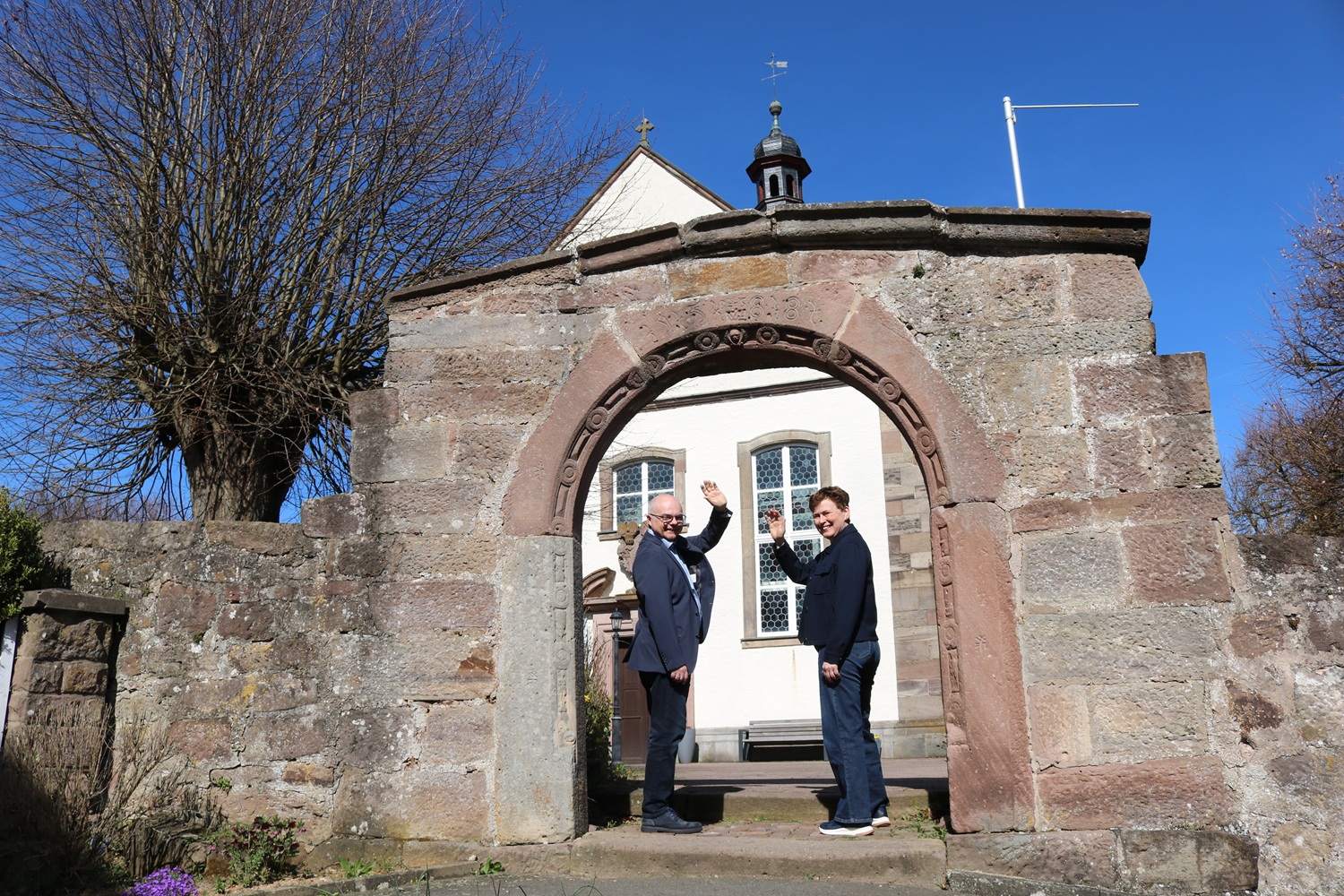 Kerstin und Michael Gütgemann Paar winkt im Tor vor einer Kirche