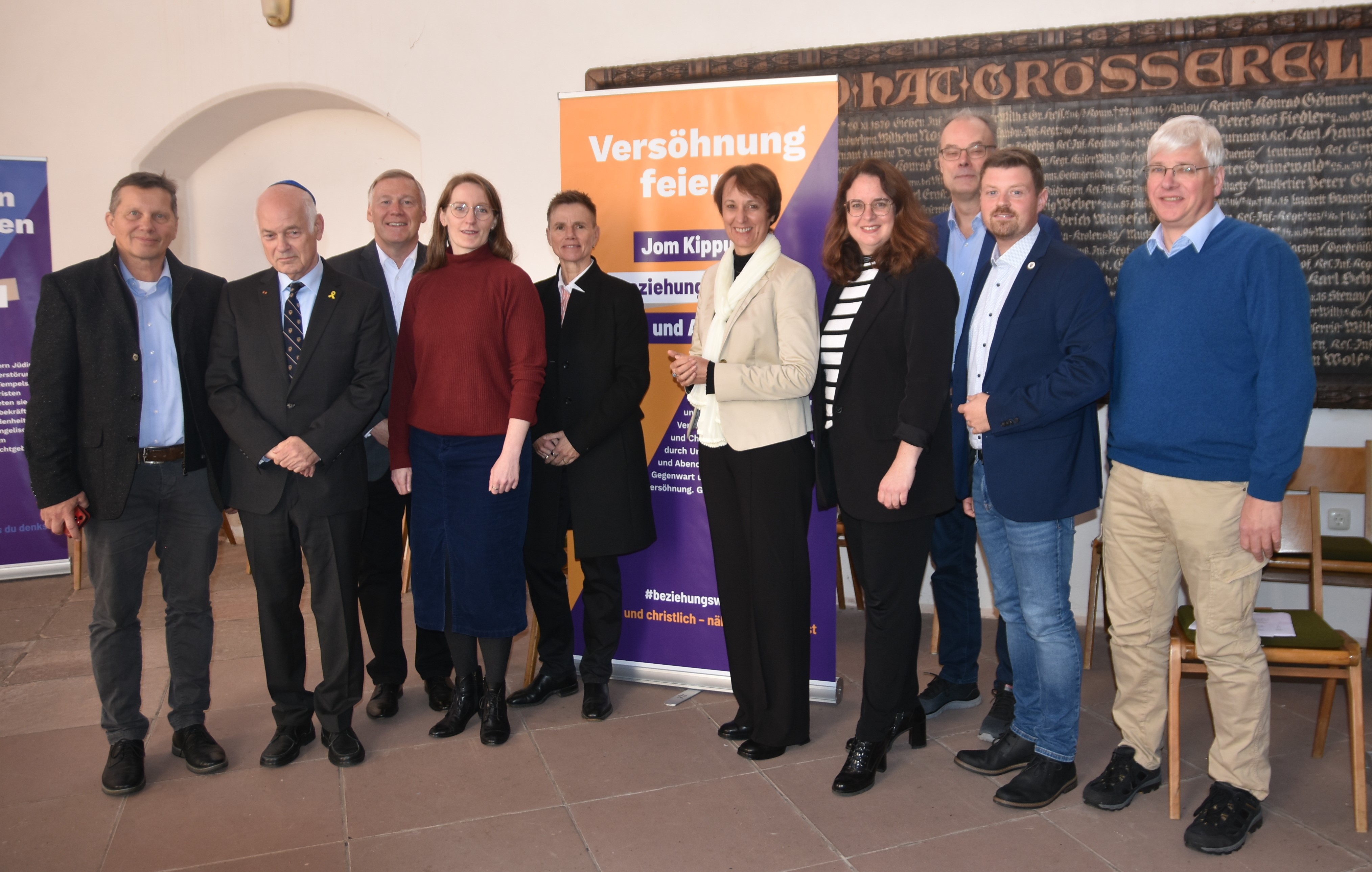 Große Gruppe von Menschen hat sich im Chorraum der Büdinger Marienkirche zu einem Gruppenfoto aufgestellt. Im Hintergrund stehen die Roll-Ups der Ausstellung.