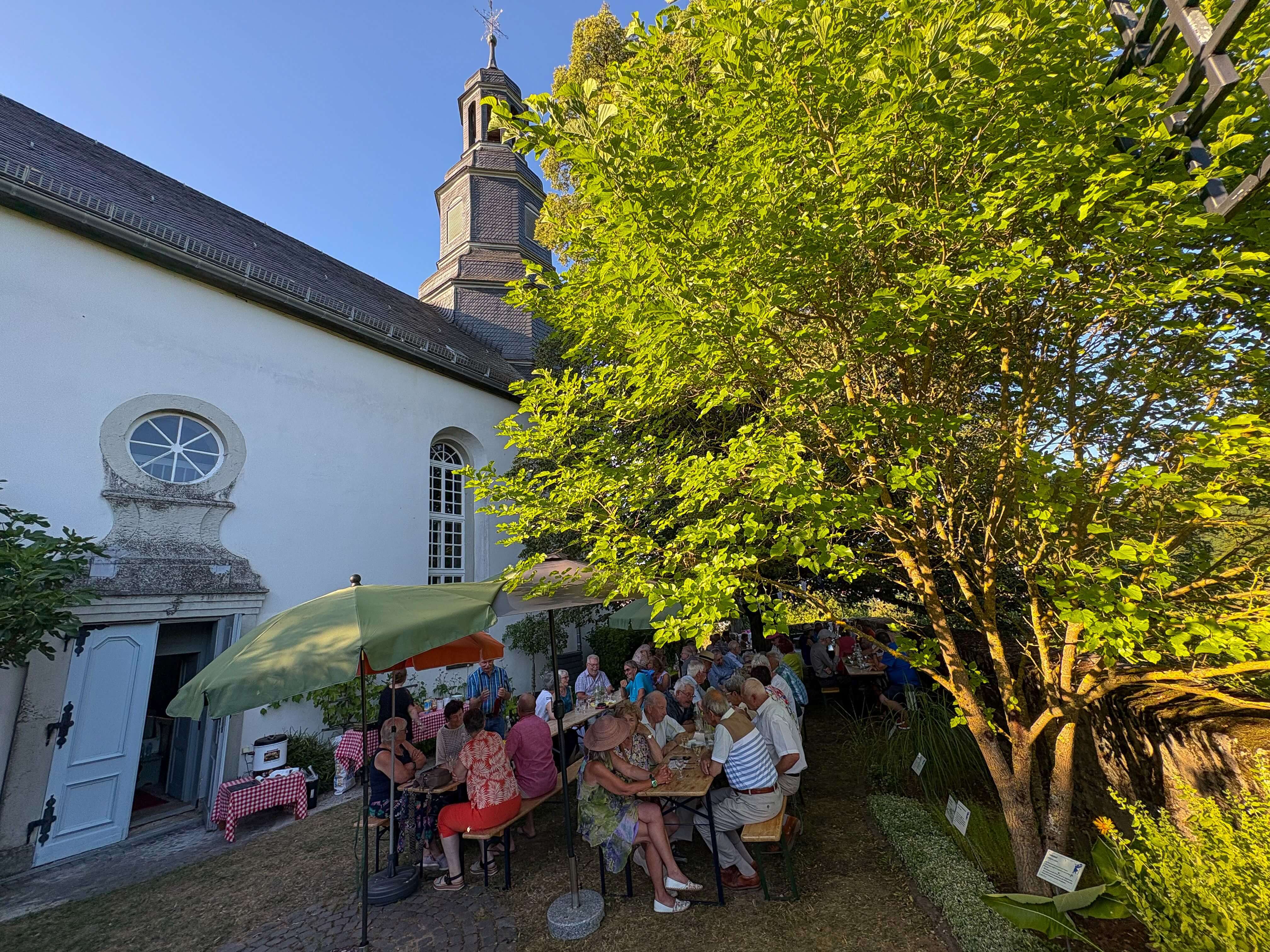 Weinfest 2026 Kirchgarten Löhnberg Menschen sitzen unter der Linde im Kirchgarten Löhnberg