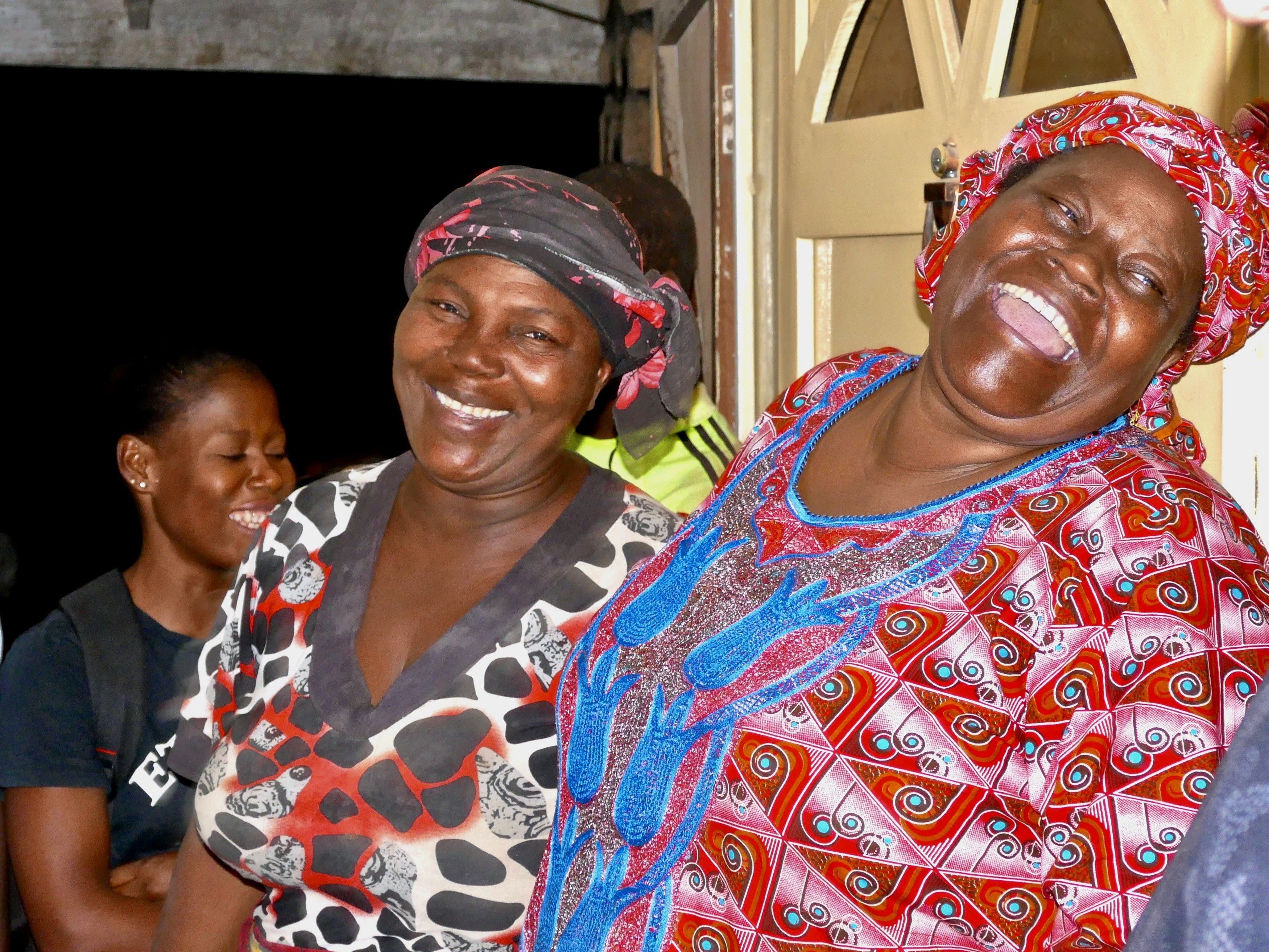 Zwei nigerianische Frauen in landestyischer farbenfroher Tracht lachen fröhlich in die Kamera
