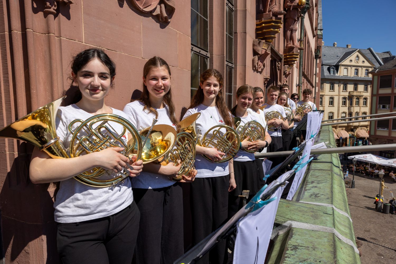 Mehrere Mädchen mit weißen Shirts und Posaunen in der Hand stehen auf dem Balkon der Frankfurter Nikolaikirche