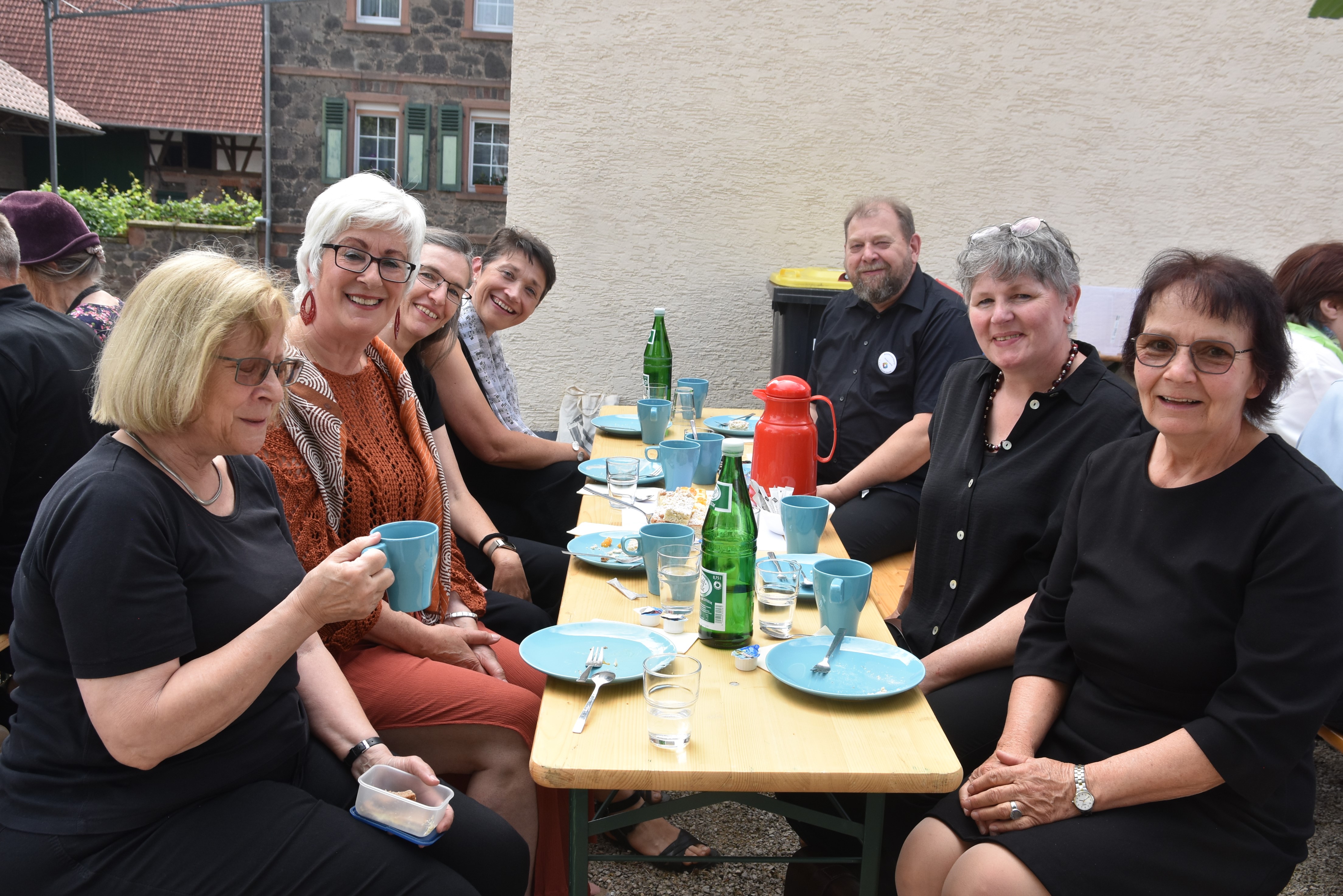 Kaffeetafel unter freiem Himmel: Sechs Frauen und ein Mann sitzen an einer Festzeltgarnitur, vor sich Kaffeegeschirr.