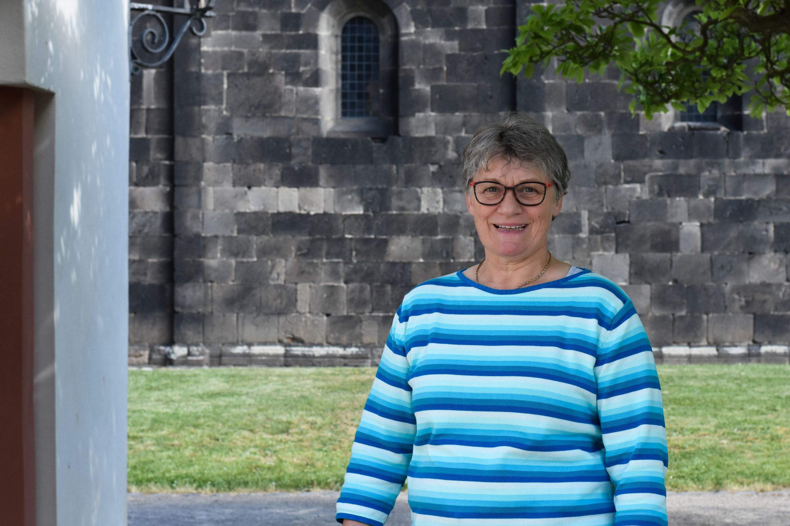 Porträt einer Frau vor einer Kirche.